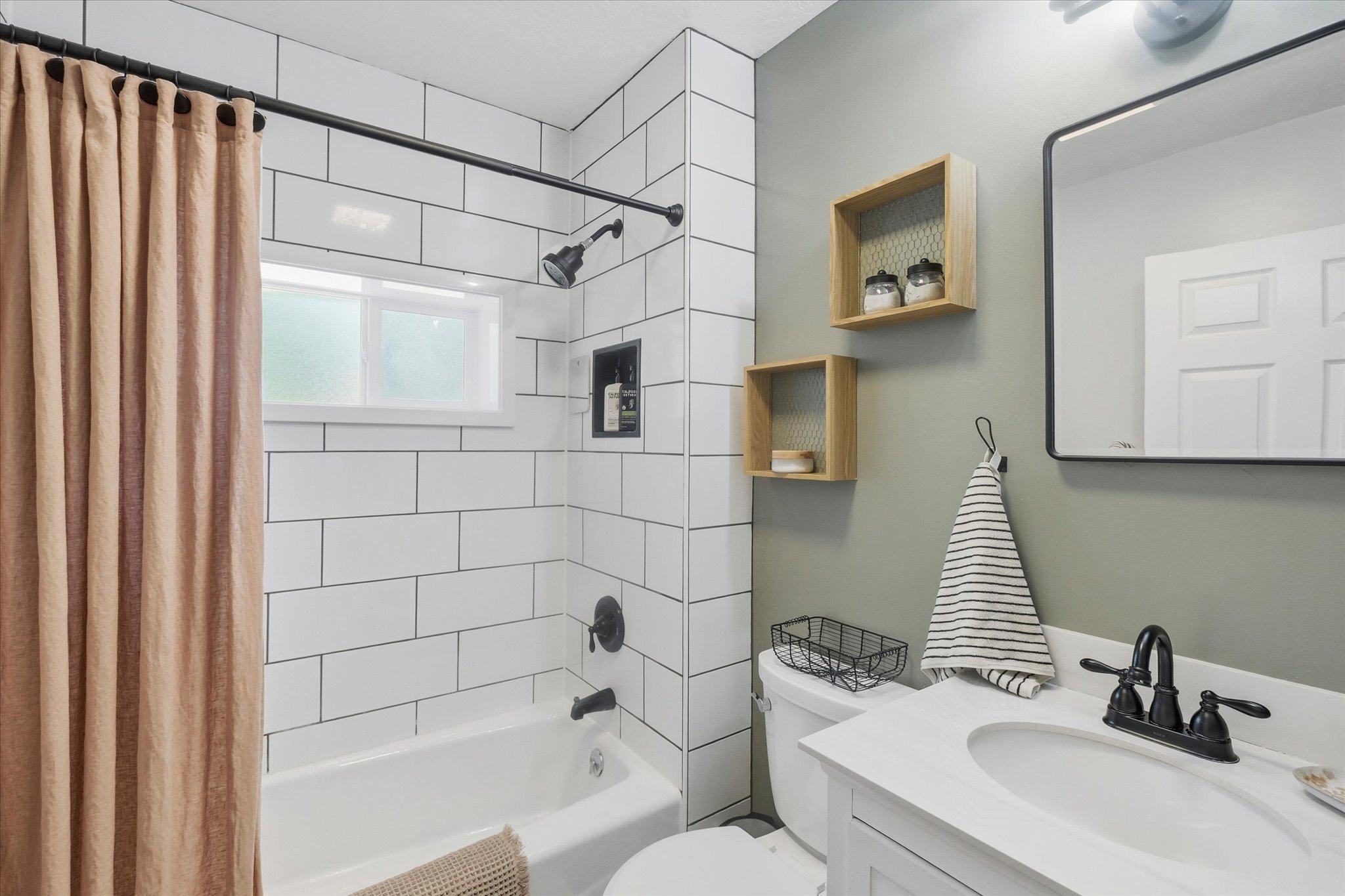 Bathroom featuring a subway tile shower with an integrated niche, a window, and matte black fixtures
