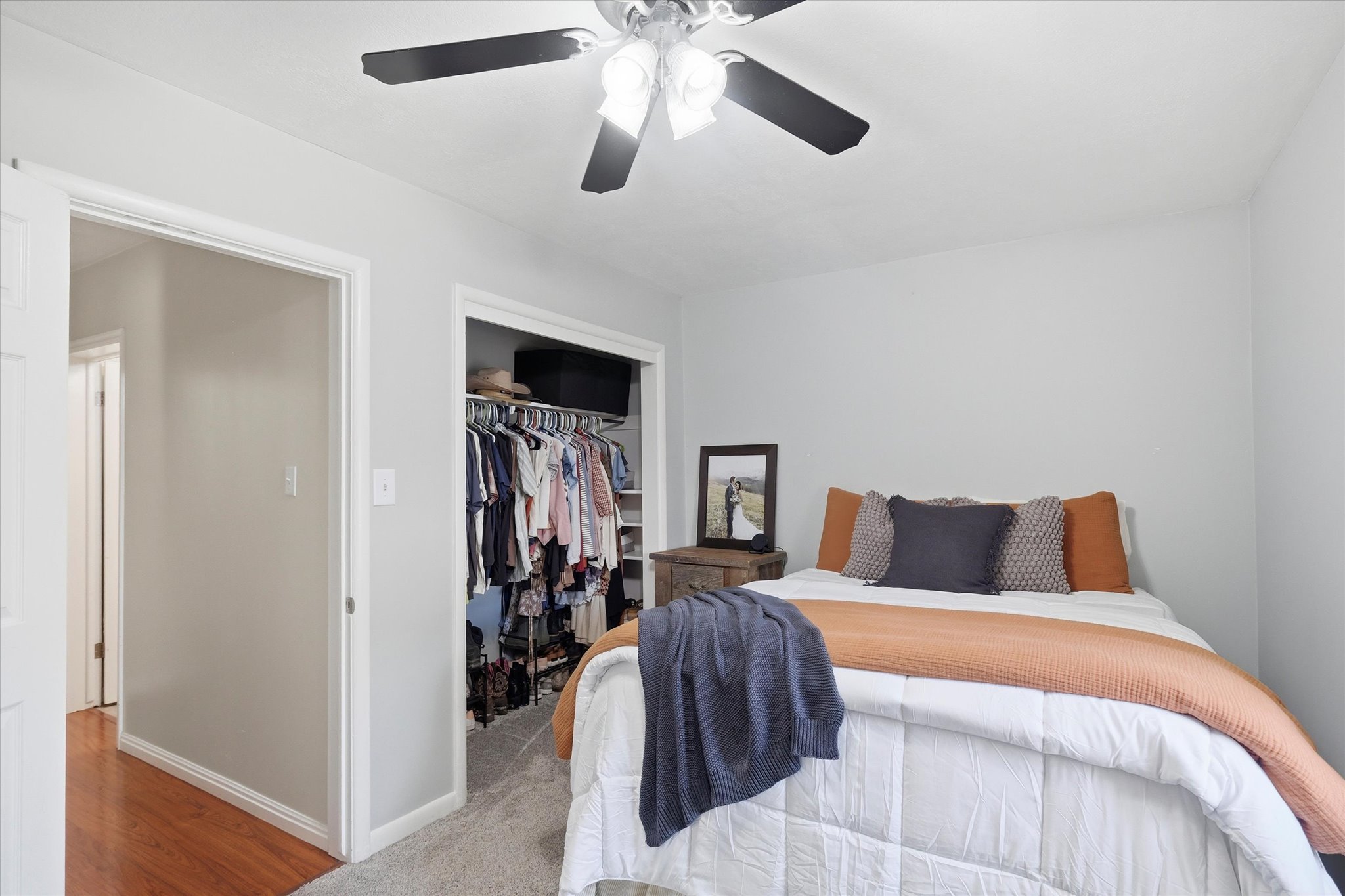 Bedroom featuring light gray wall paint, a ceiling fan with integrated lighting, and a closet with built-in shelving