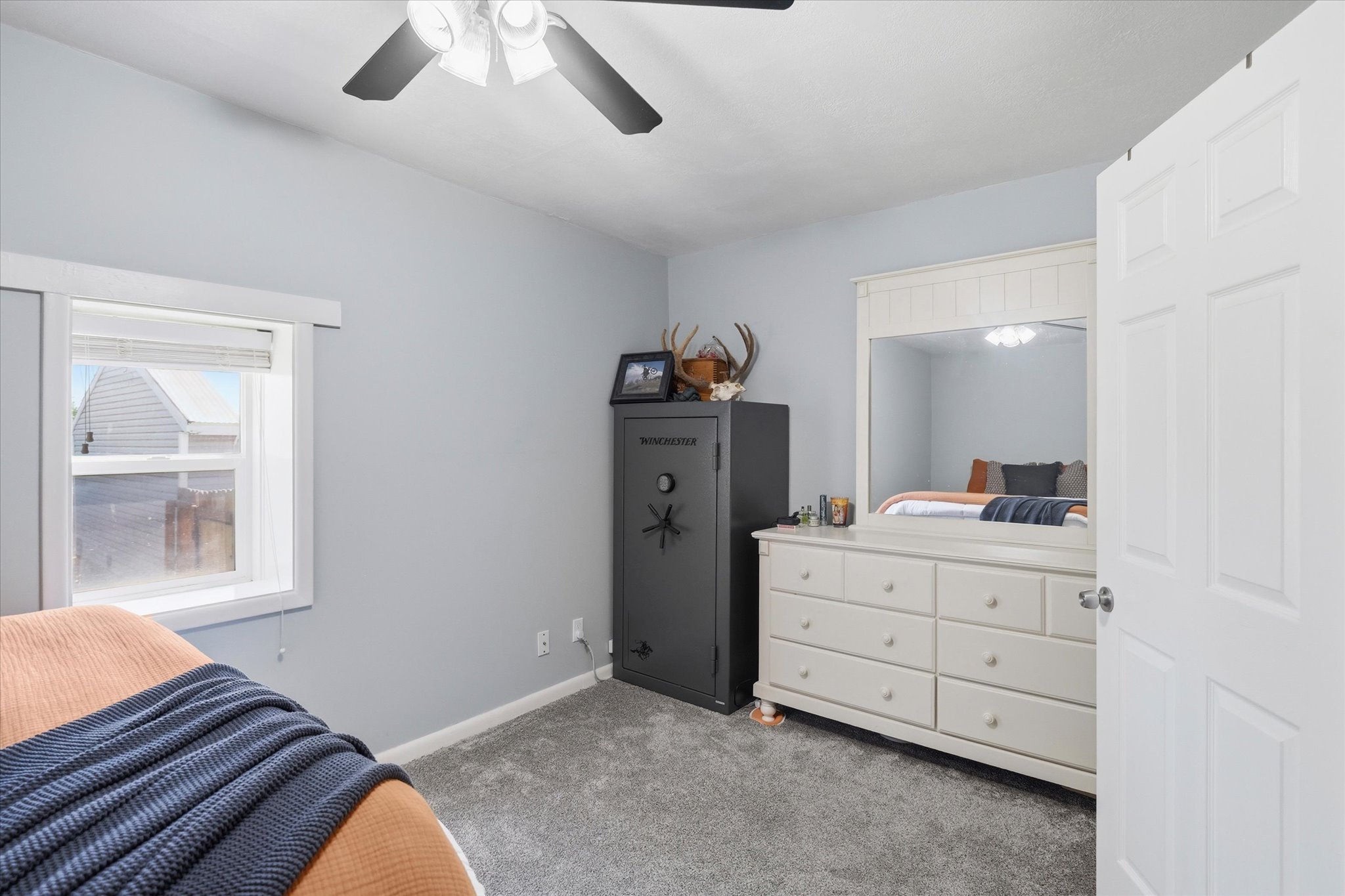 Bedroom featuring a window with white trim, light gray walls, and gray carpet flooring