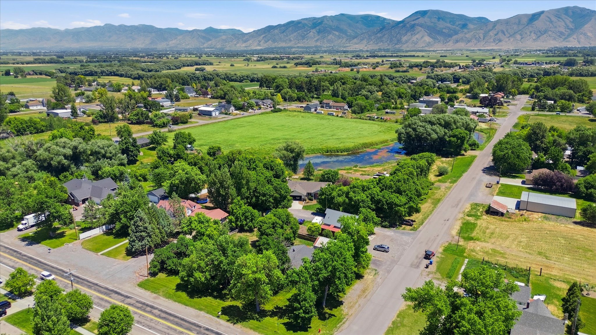 Expansive aerial perspective showcasing a verdant landscape with a prominent body of water, bordered by paved roadways and mature trees