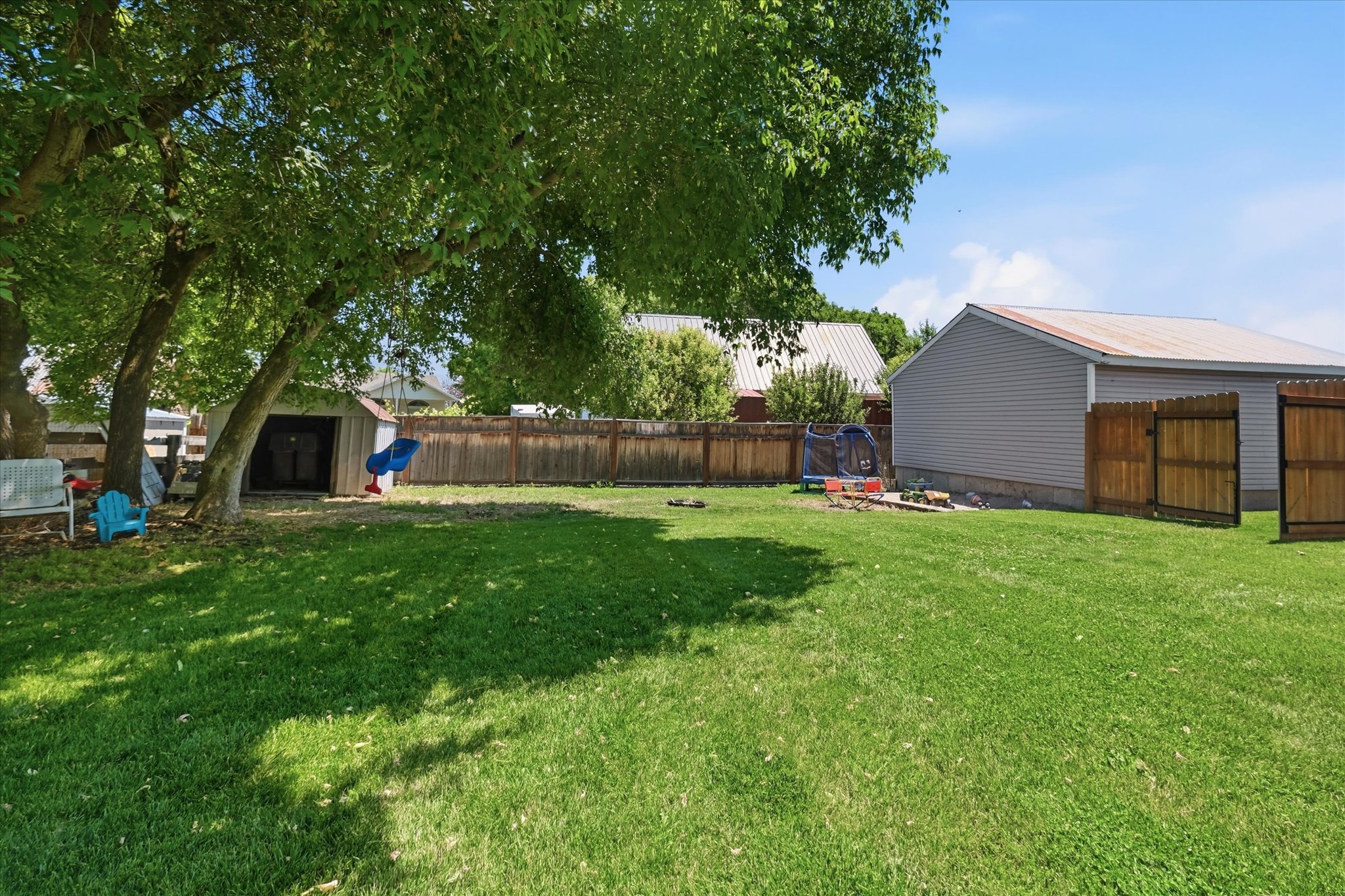 Expansive green lawn with mature trees providing partial shade