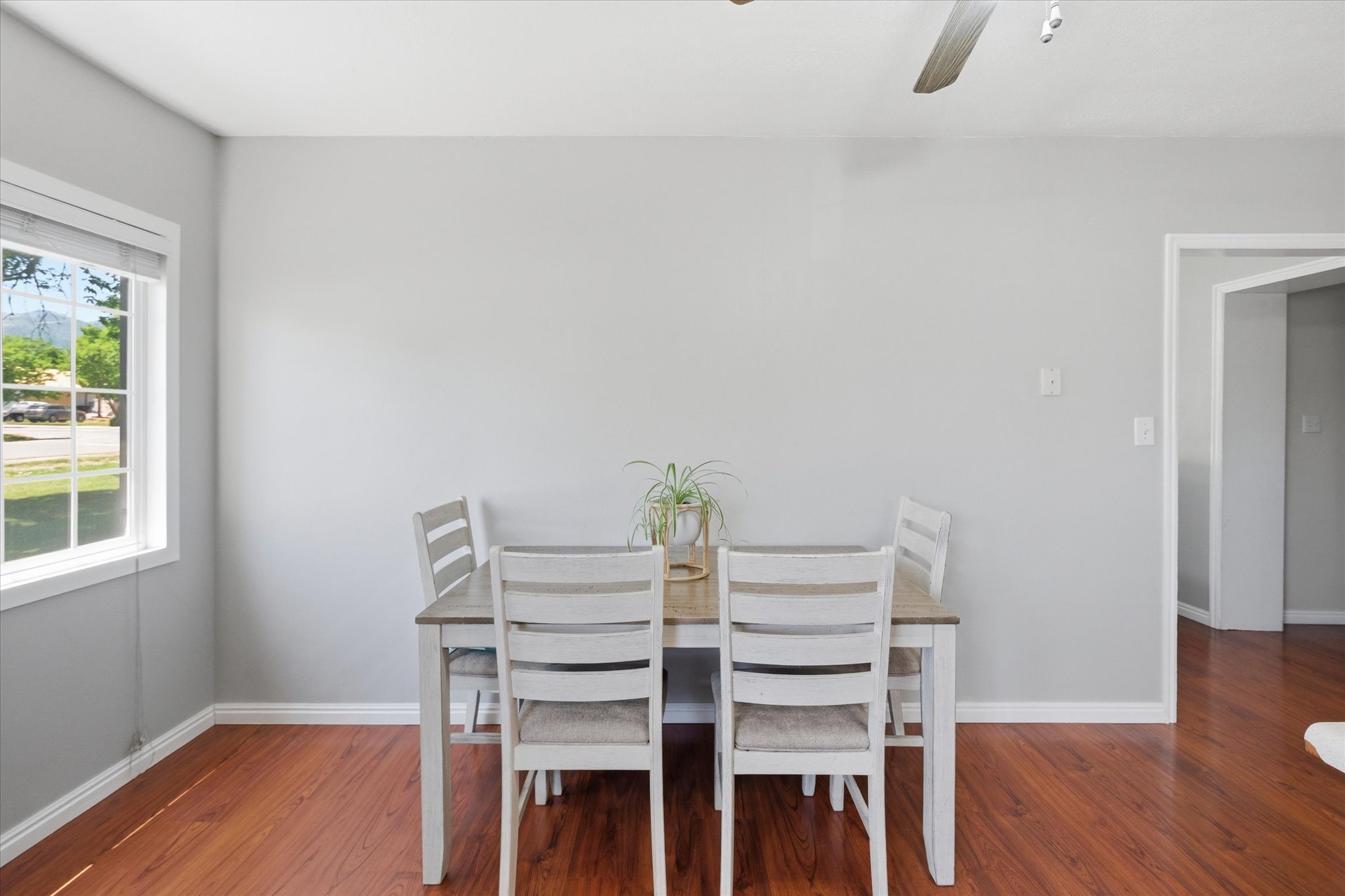 Spacious room featuring wood-finish flooring, light gray wall paint, and white baseboards