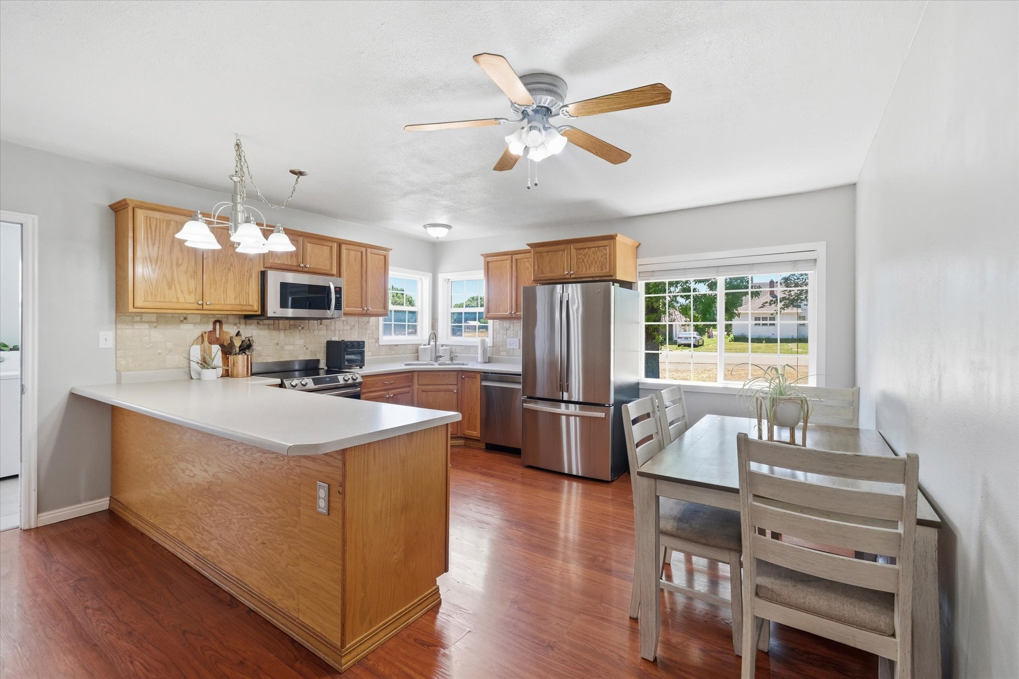 Kitchen featuring wood-finish flooring, light wood cabinetry, stainless steel appliances, and a central island with a light countertop