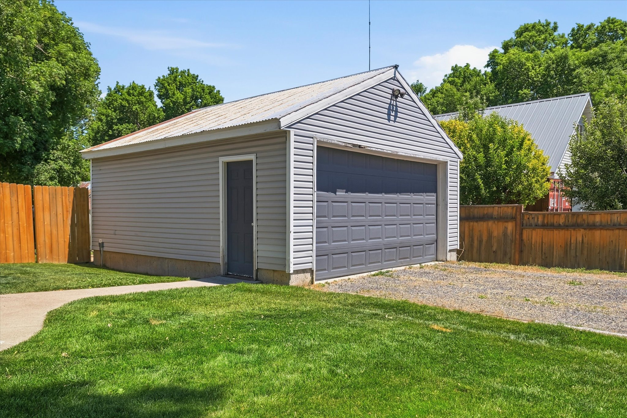 Detached garage featuring horizontal siding, a corrugated metal roof, a single entry door, and a paneled garage door