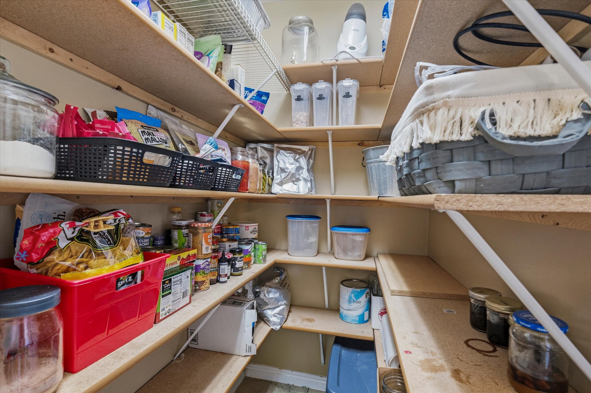 Walk-in pantry featuring light wood-finish shelving and white wire shelving