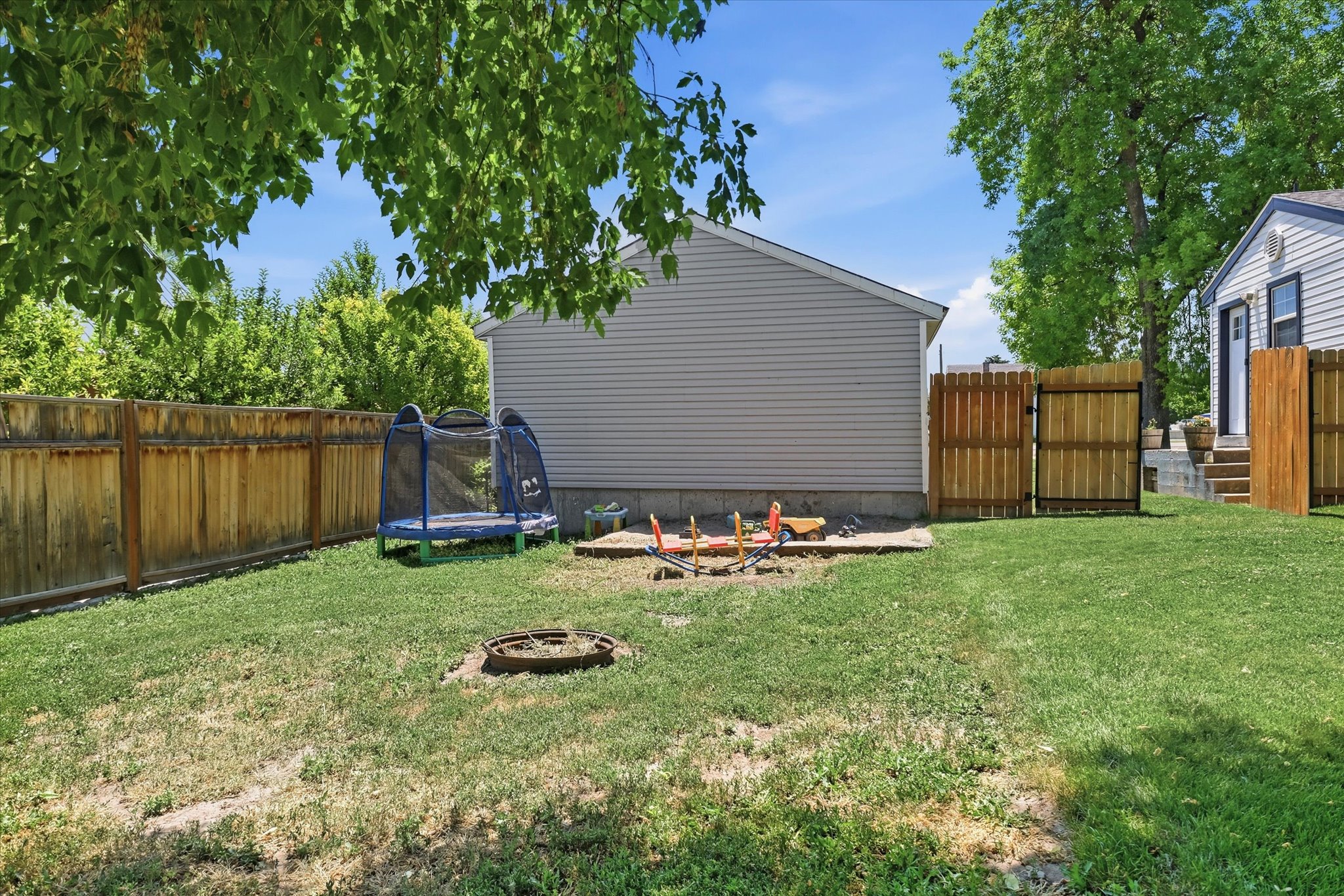 Fenced backyard featuring a manicured lawn, wood privacy fencing, and a separate building with horizontal siding