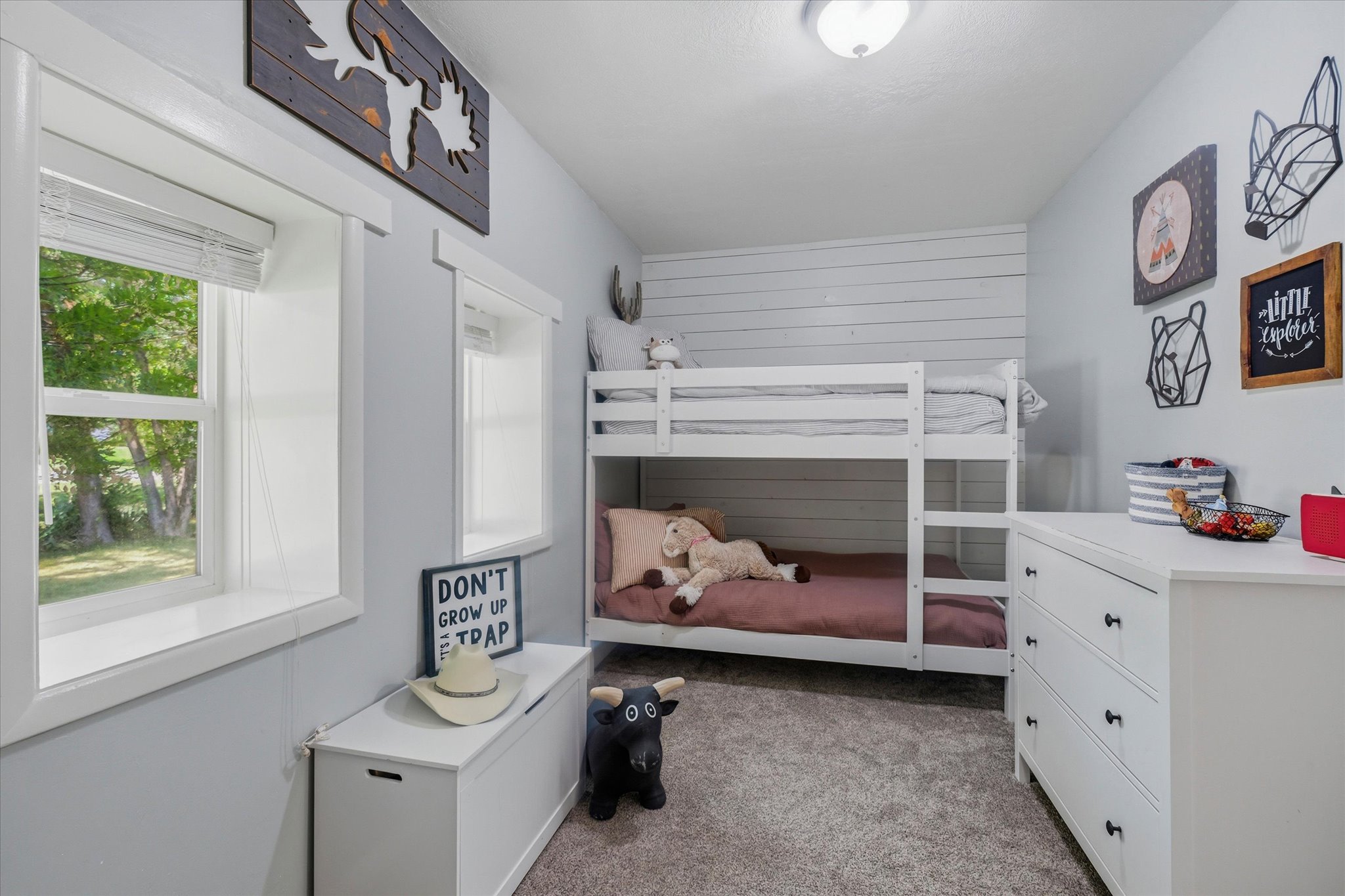 Room featuring neutral wall tones, two windows with white trim, a built-in bunk bed structure, and shiplap accent wall