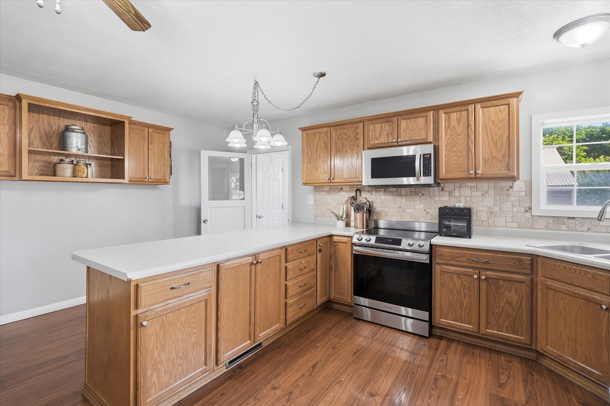 Kitchen featuring wood-finish flooring, ample wood cabinetry, a built-in stainless steel microwave, and a stainless steel range