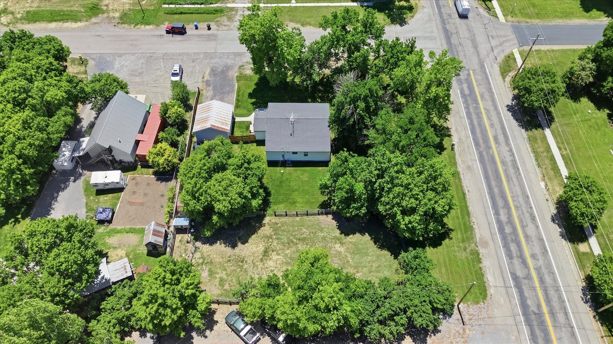 Aerial view of a property featuring a single-story residence with a gray shingle roof