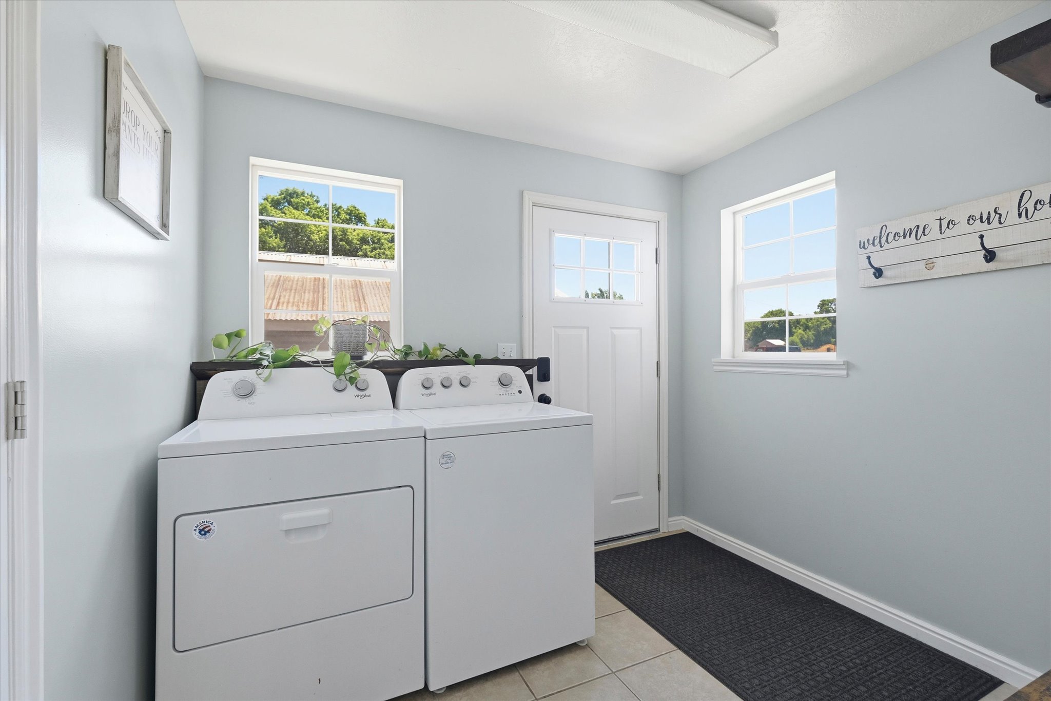 Utility room featuring a light blue wall color, white trim, and two windows