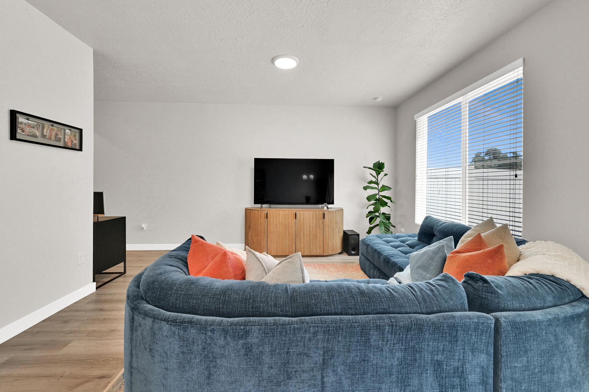 Open-concept living area featuring wood-finish flooring, a large window with blinds, and recessed lighting