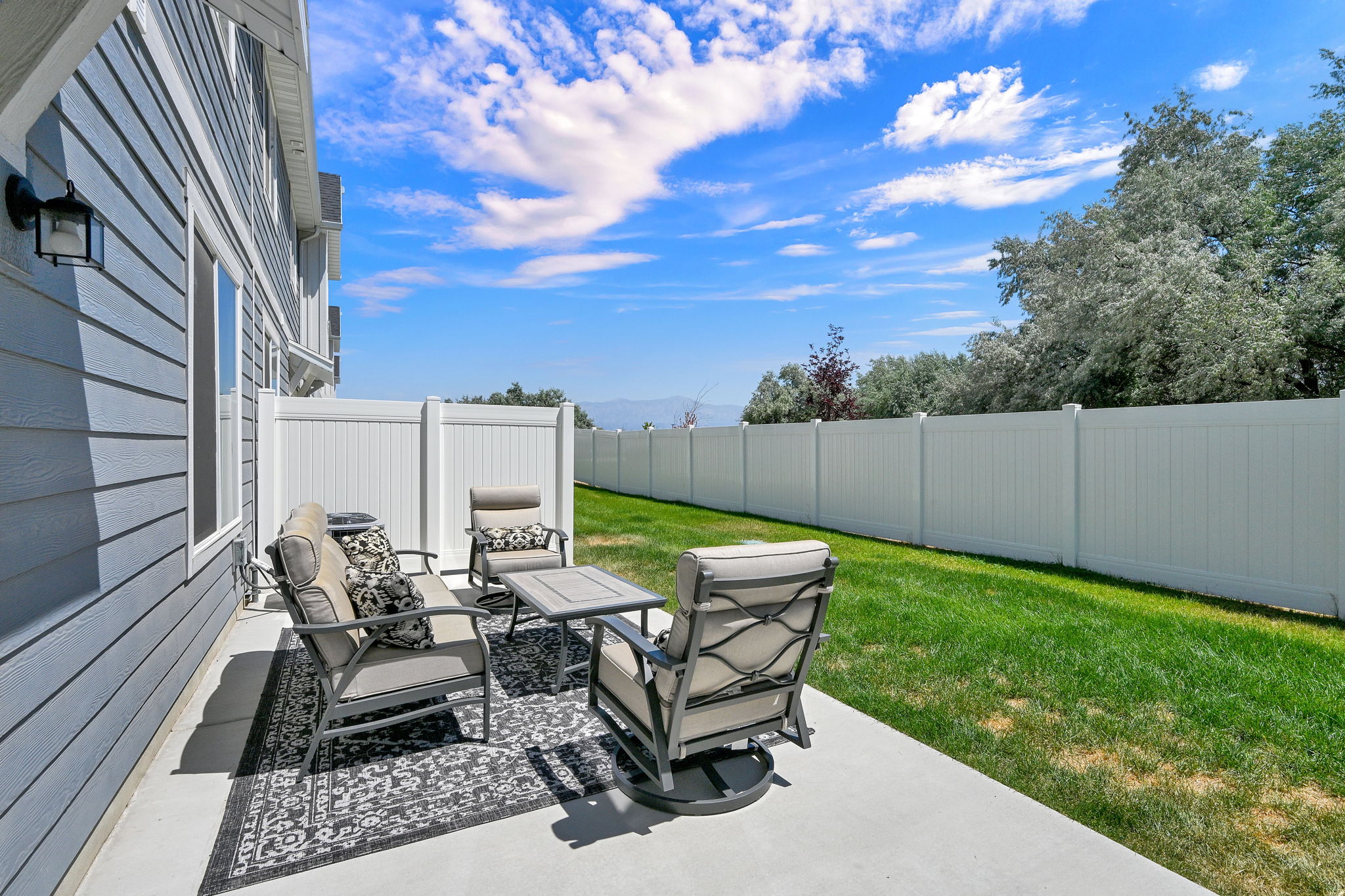 Concrete patio featuring a privacy fence, manicured lawn, and exterior siding