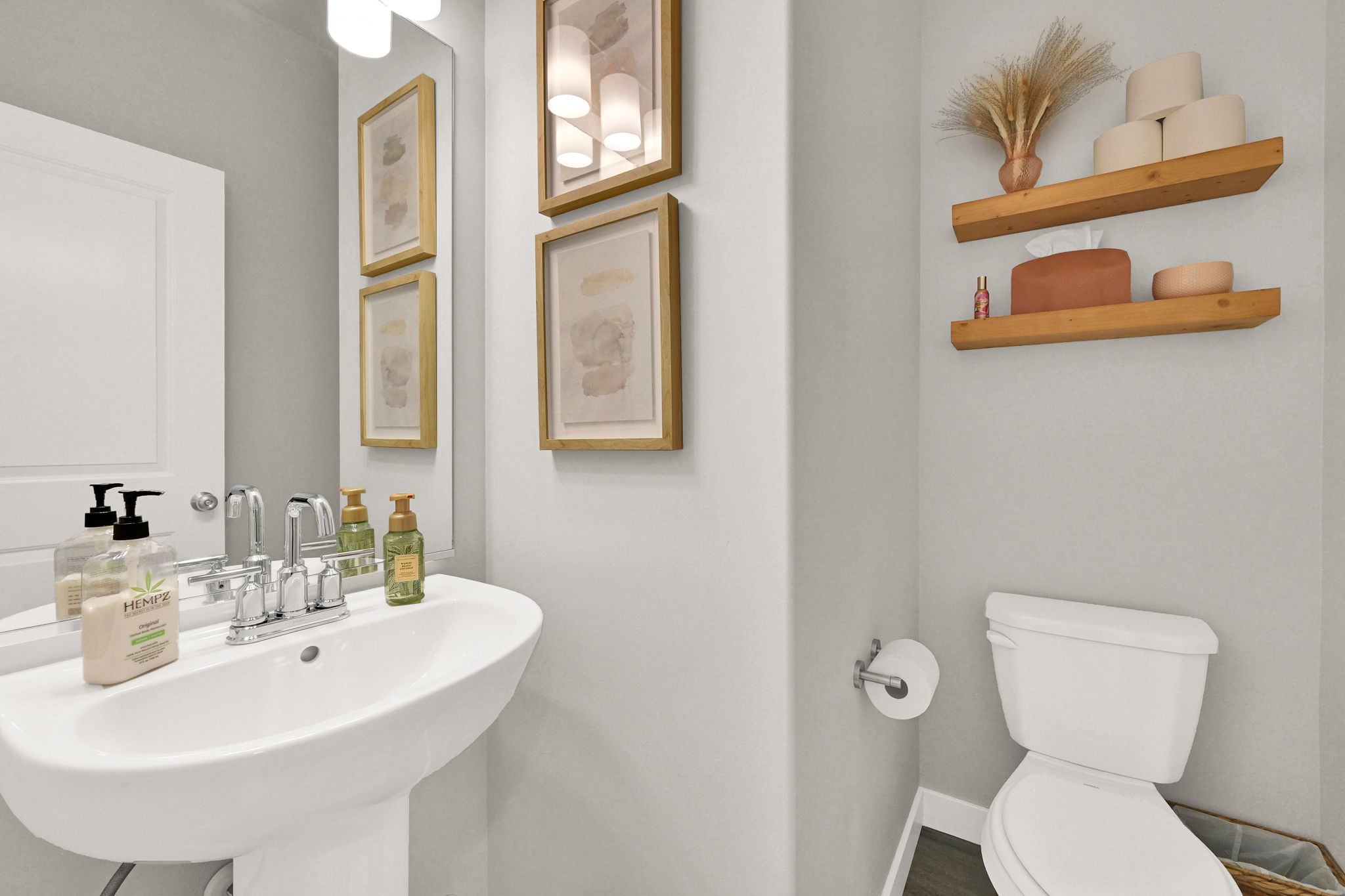 Pedestal sink with chrome faucet, complemented by a mirror and wall-mounted light fixture