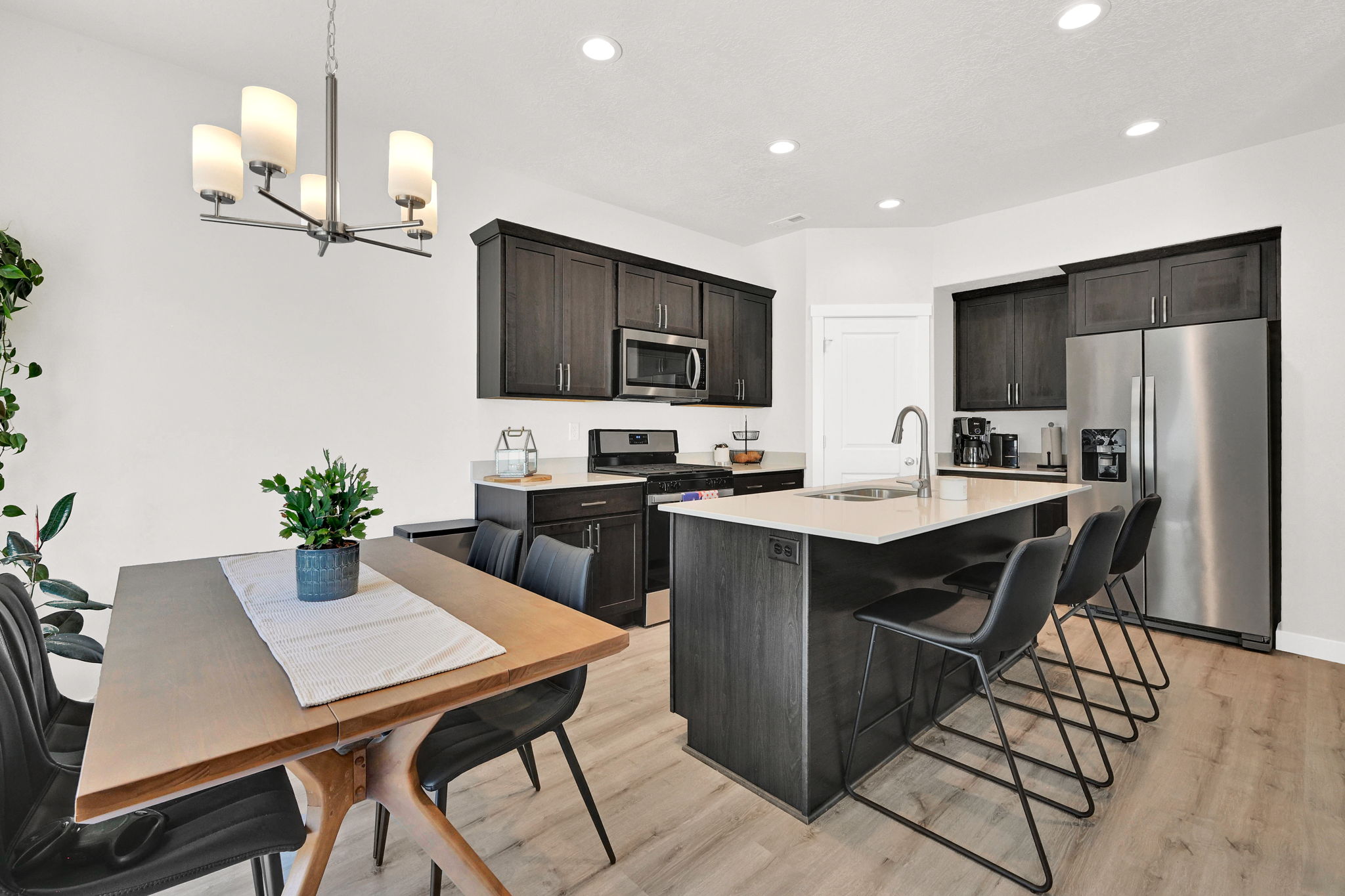 Open-concept kitchen and dining area featuring dark wood-finish cabinetry, light countertops, and stainless steel appliances