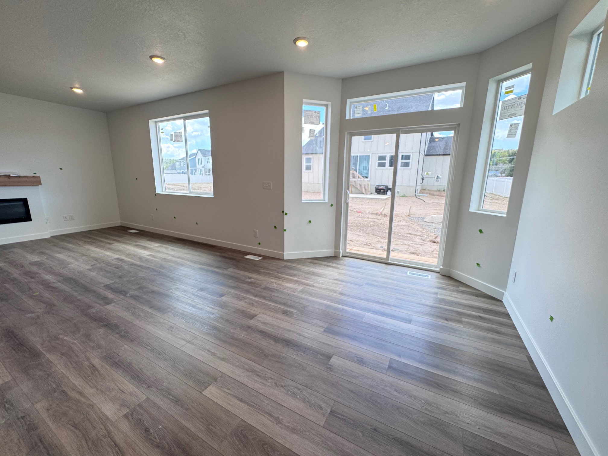 Spacious room featuring wood-finish flooring, a contemporary electric fireplace with a wood mantle, and recessed ceiling lighting