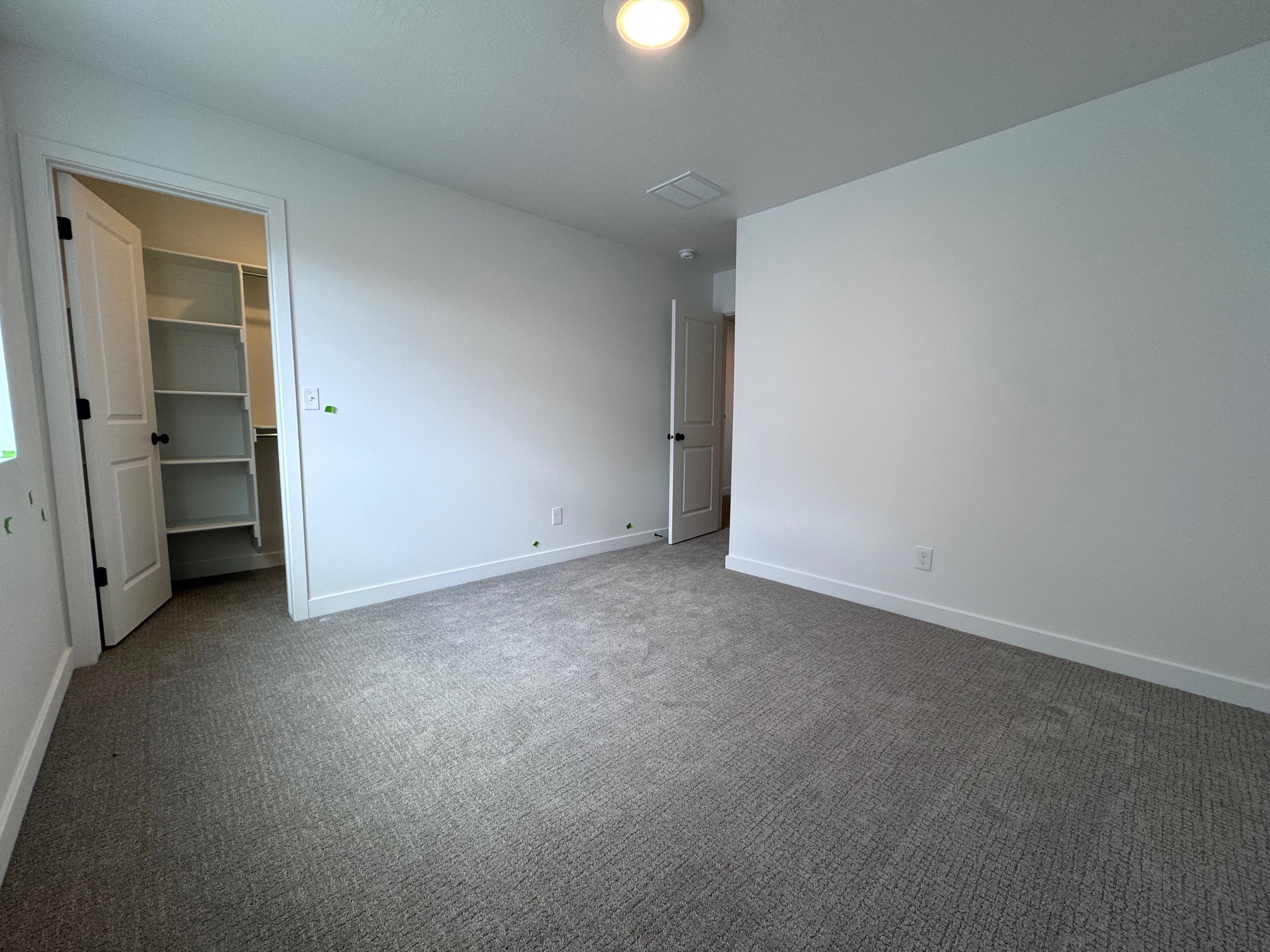 Carpeted room featuring a ceiling-mounted light fixture, white walls, and white baseboards