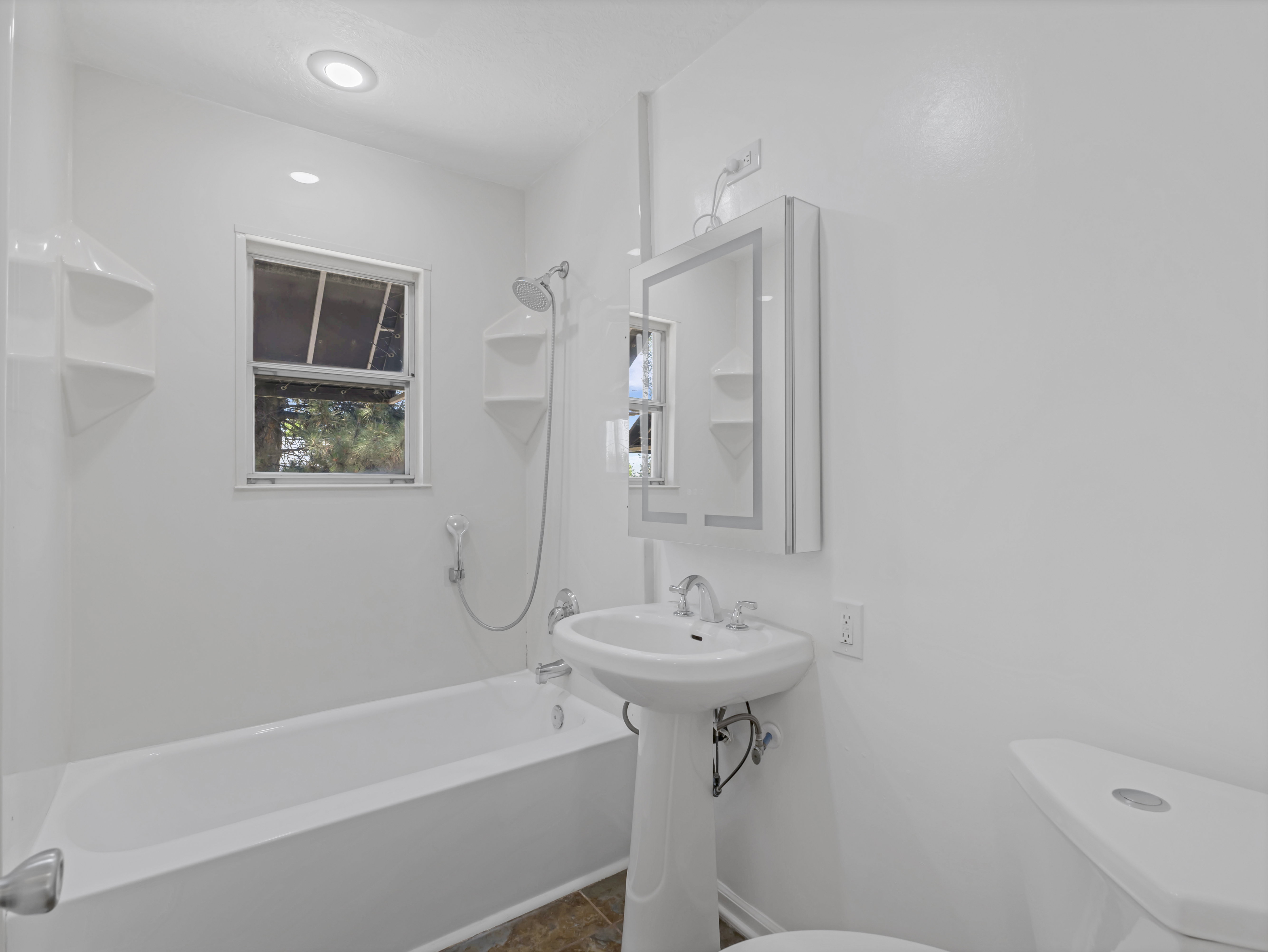 Bathroom featuring a pedestal sink, white toilet, and tub with shower combination