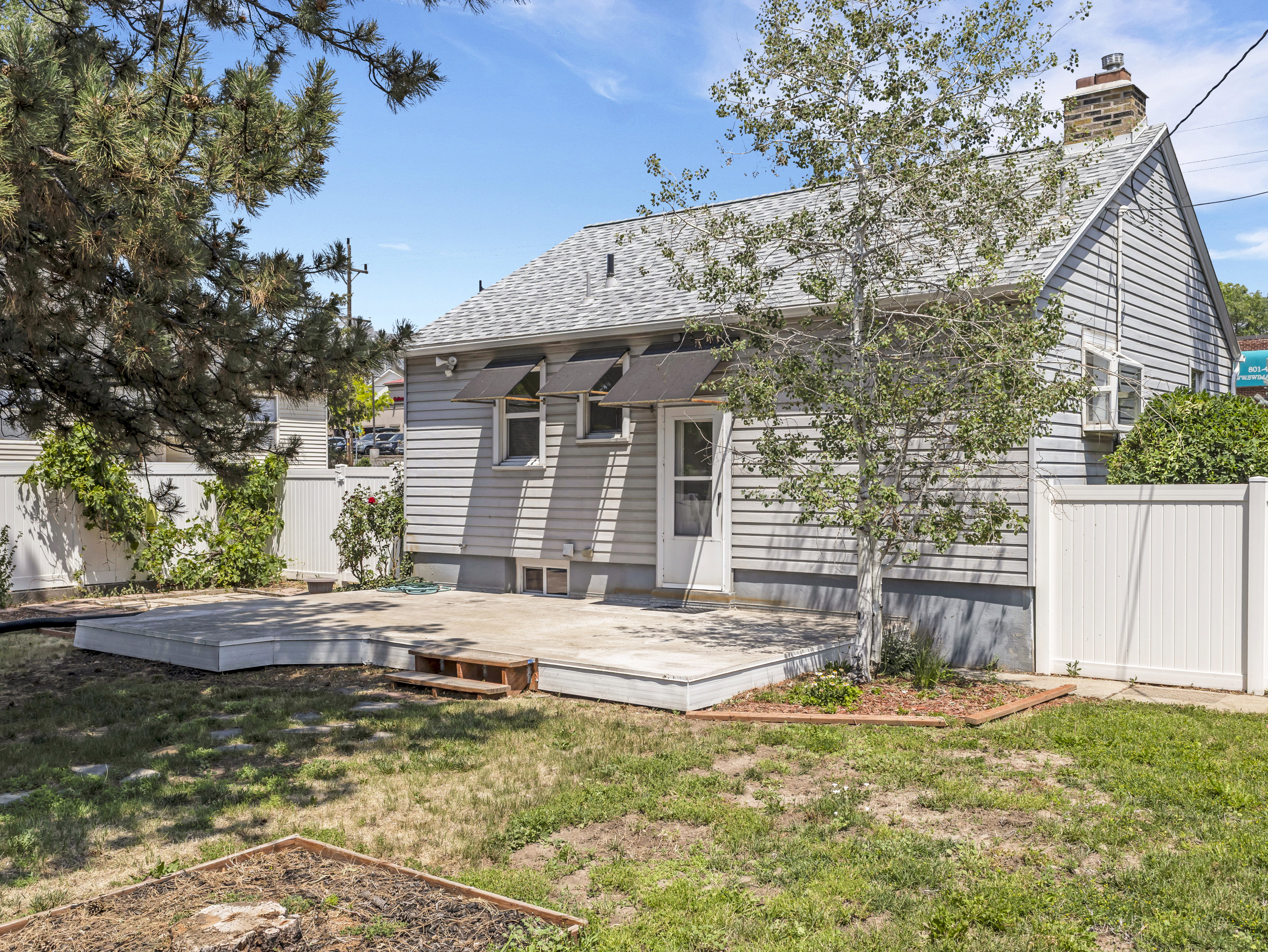 Rear exterior featuring a spacious elevated deck, light gray siding, and a white privacy fence
