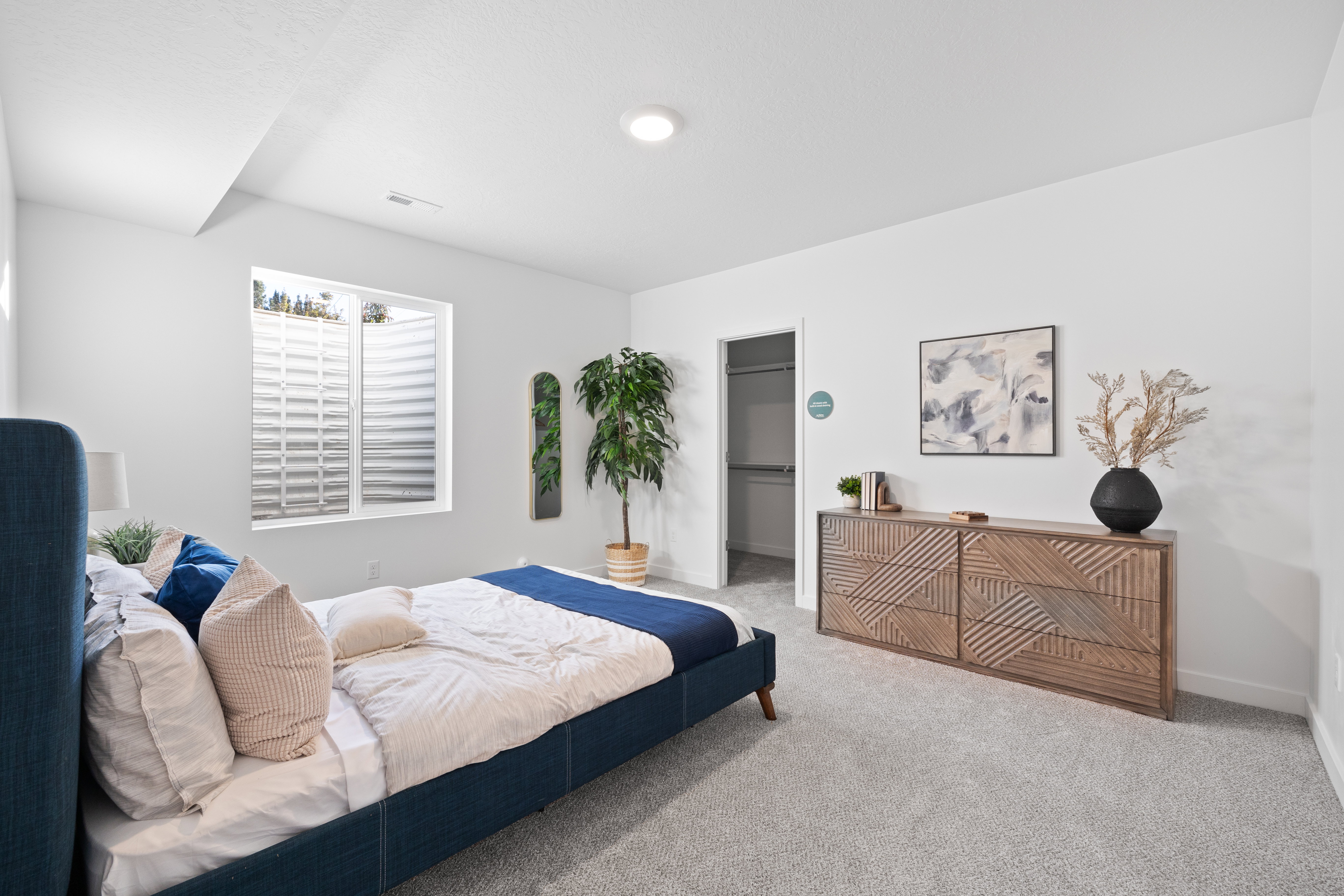 Recessed lighting illuminates a space featuring light gray carpeting and white walls
