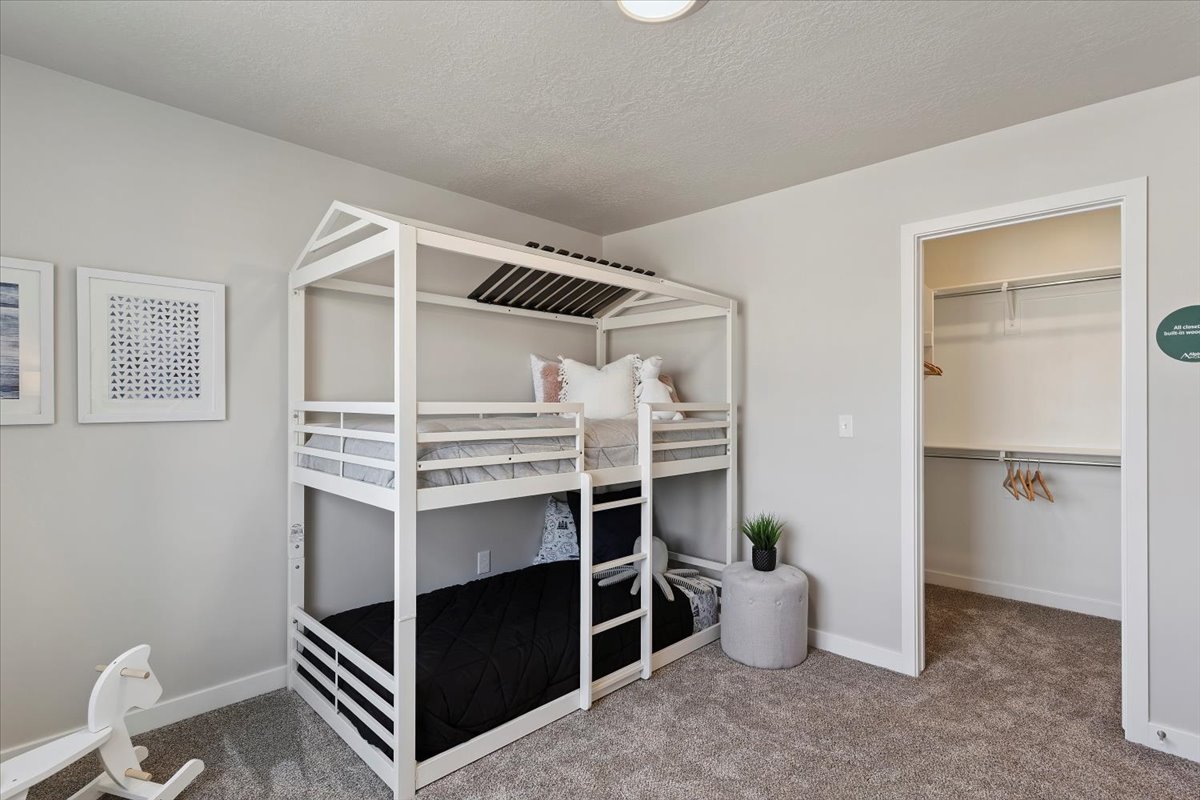 Carpeted room featuring light gray walls, a built-in closet with shelving and hanging rods, and a flush-mount ceiling light fixture