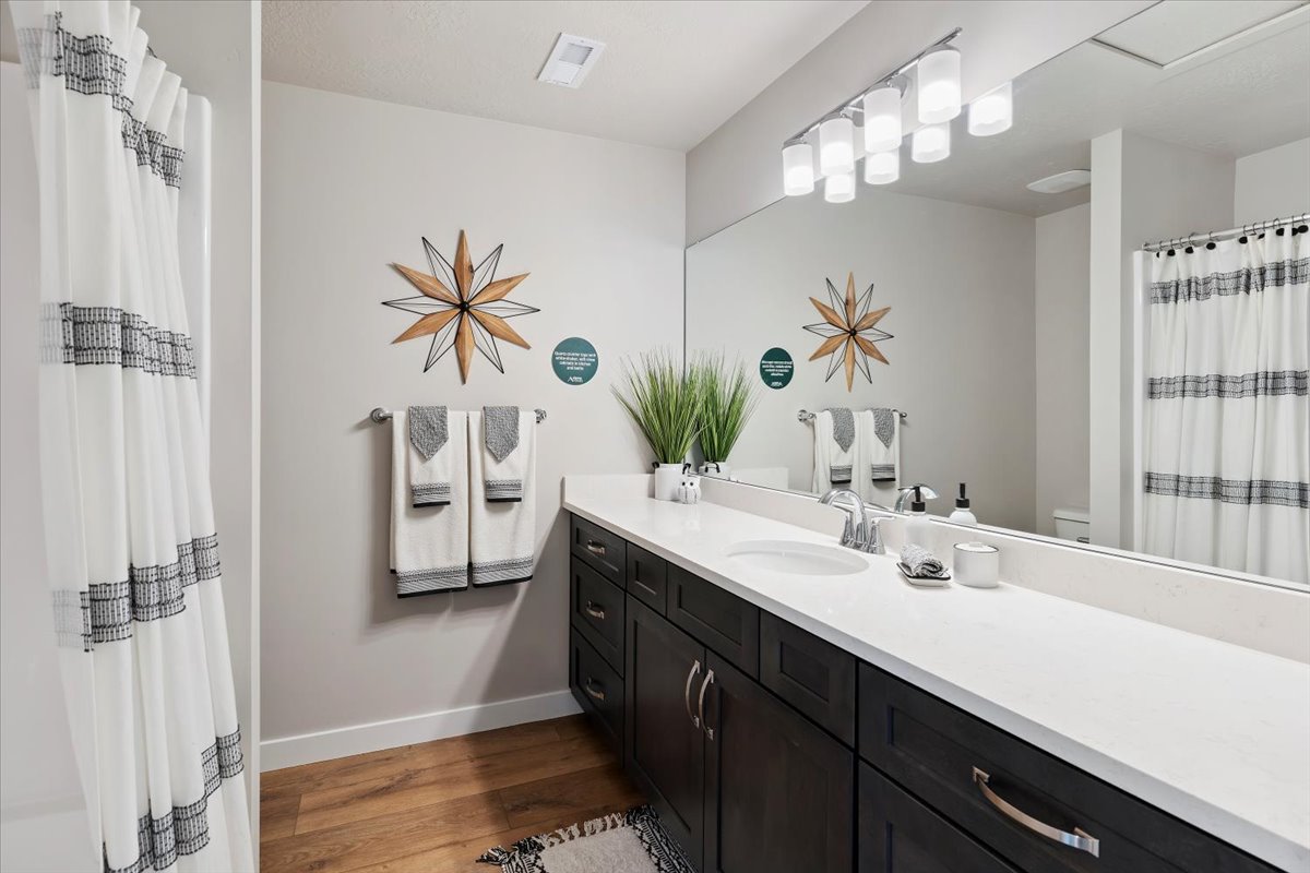 Contemporary bathroom featuring a dark wood-finish vanity with ample storage, a white countertop, and an integrated sink with a chrome faucet