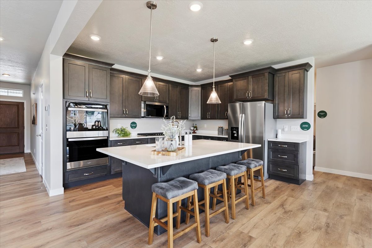 Spacious kitchen featuring dark cabinetry, stainless steel appliances, and a large central island with seating