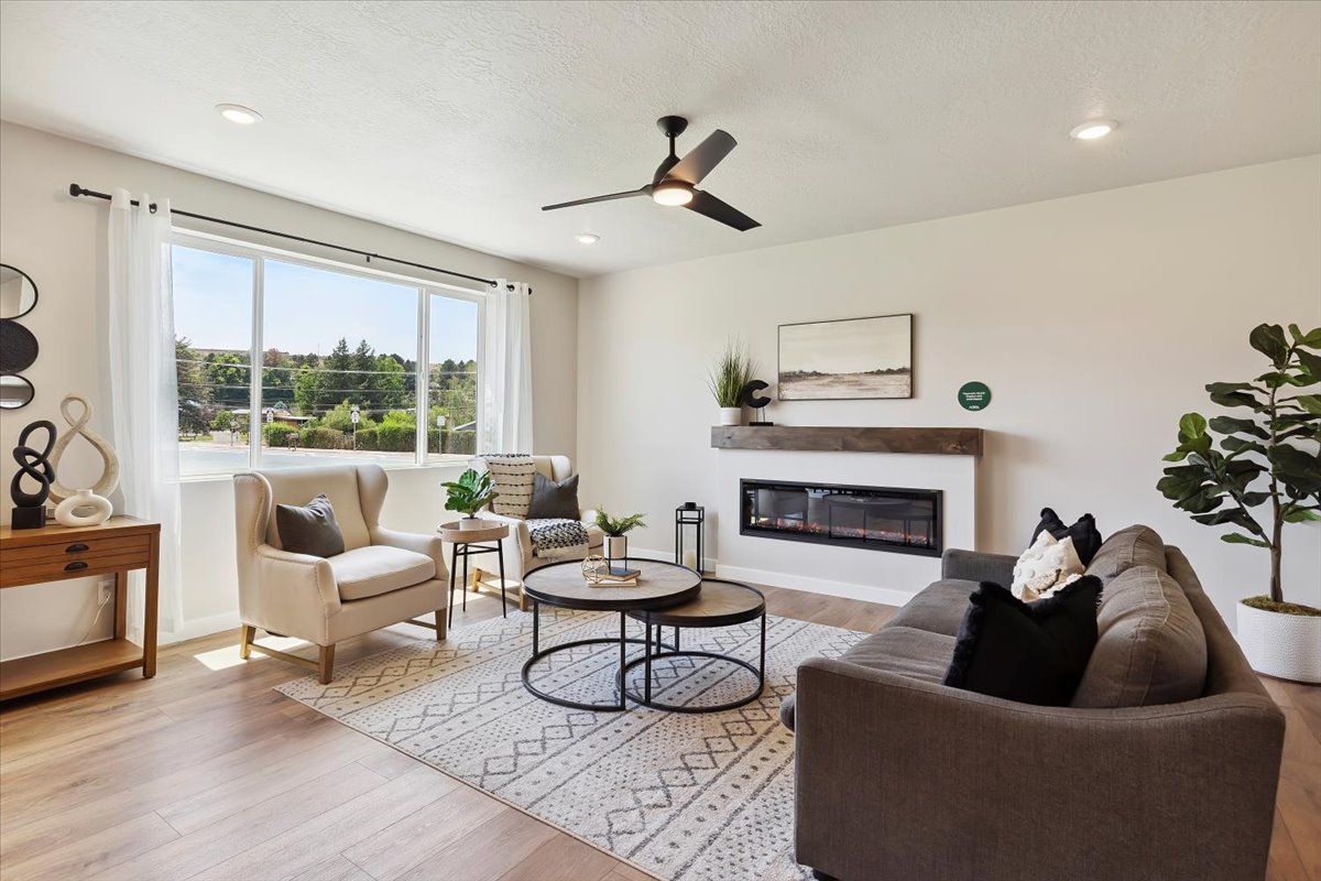 Spacious living area featuring expansive windows, wood-finish flooring, recessed lighting, and a linear electric fireplace with a wood mantle