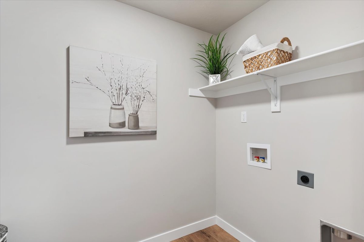 Laundry area with wood-finish flooring, light grey walls, and white trim