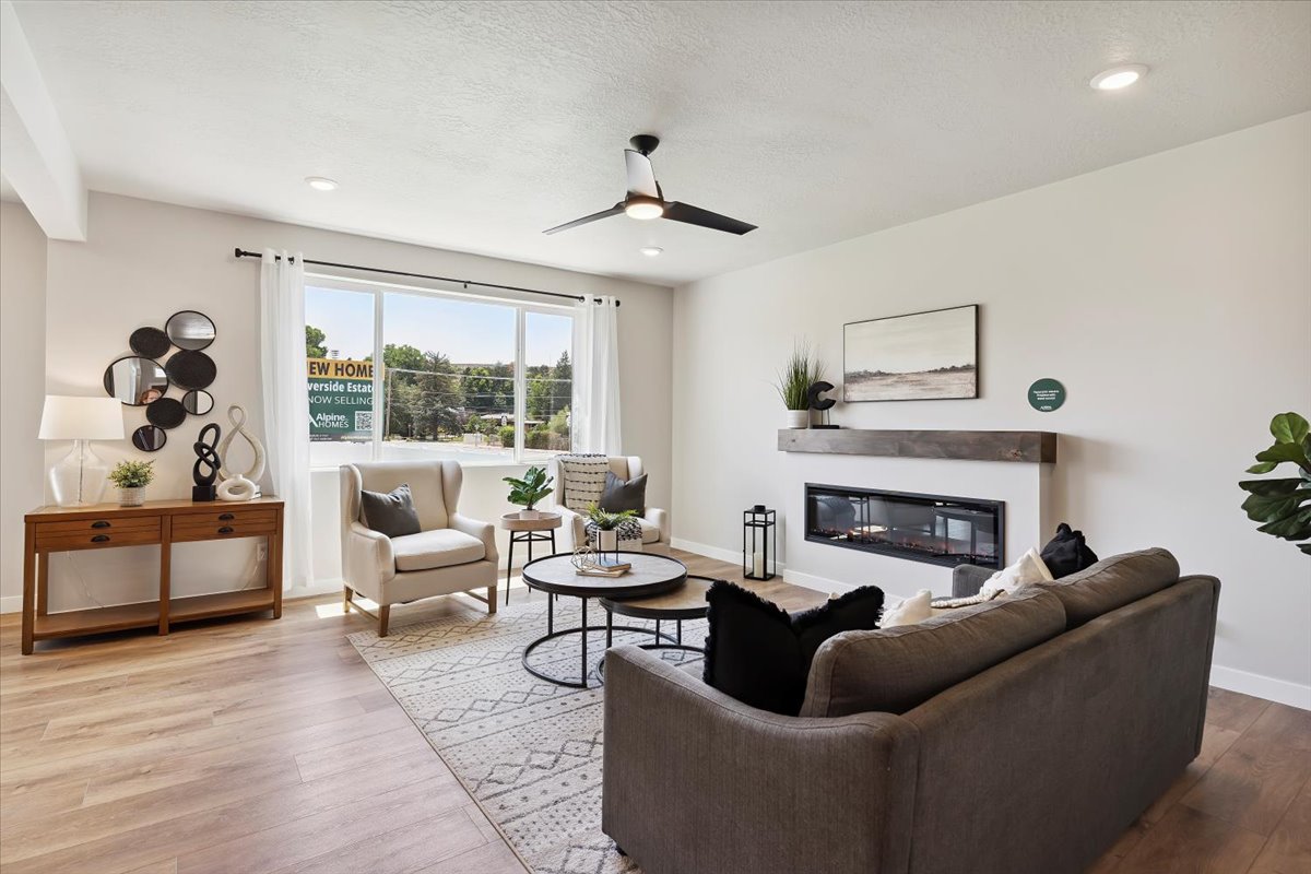 Spacious living area featuring wood-finish flooring, a linear electric fireplace with a wood mantle, a ceiling fan, recessed lighting, and a large picture window
