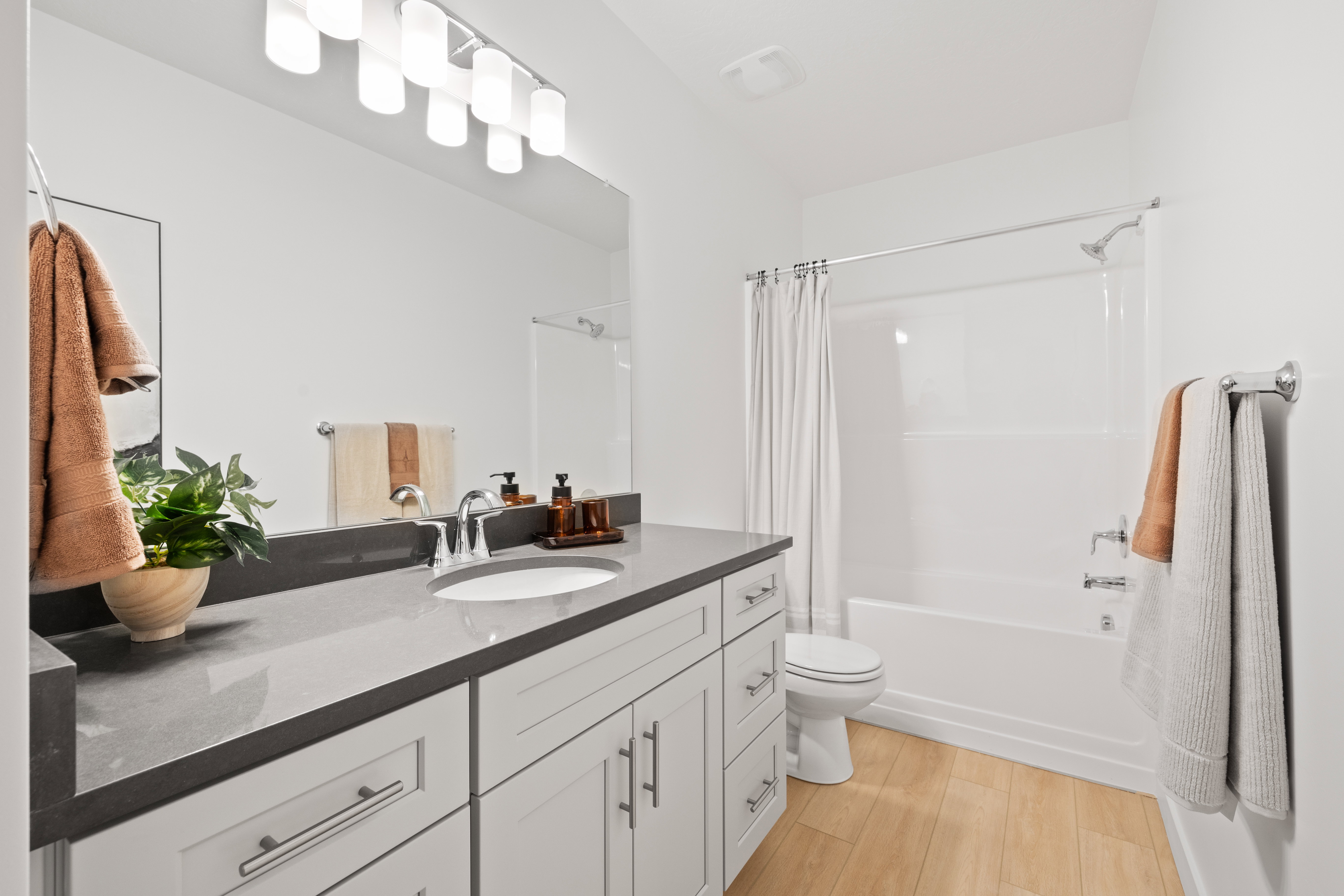 Bathroom featuring a white vanity with shaker-style cabinetry, a gray countertop, an undermount sink, and a chrome faucet