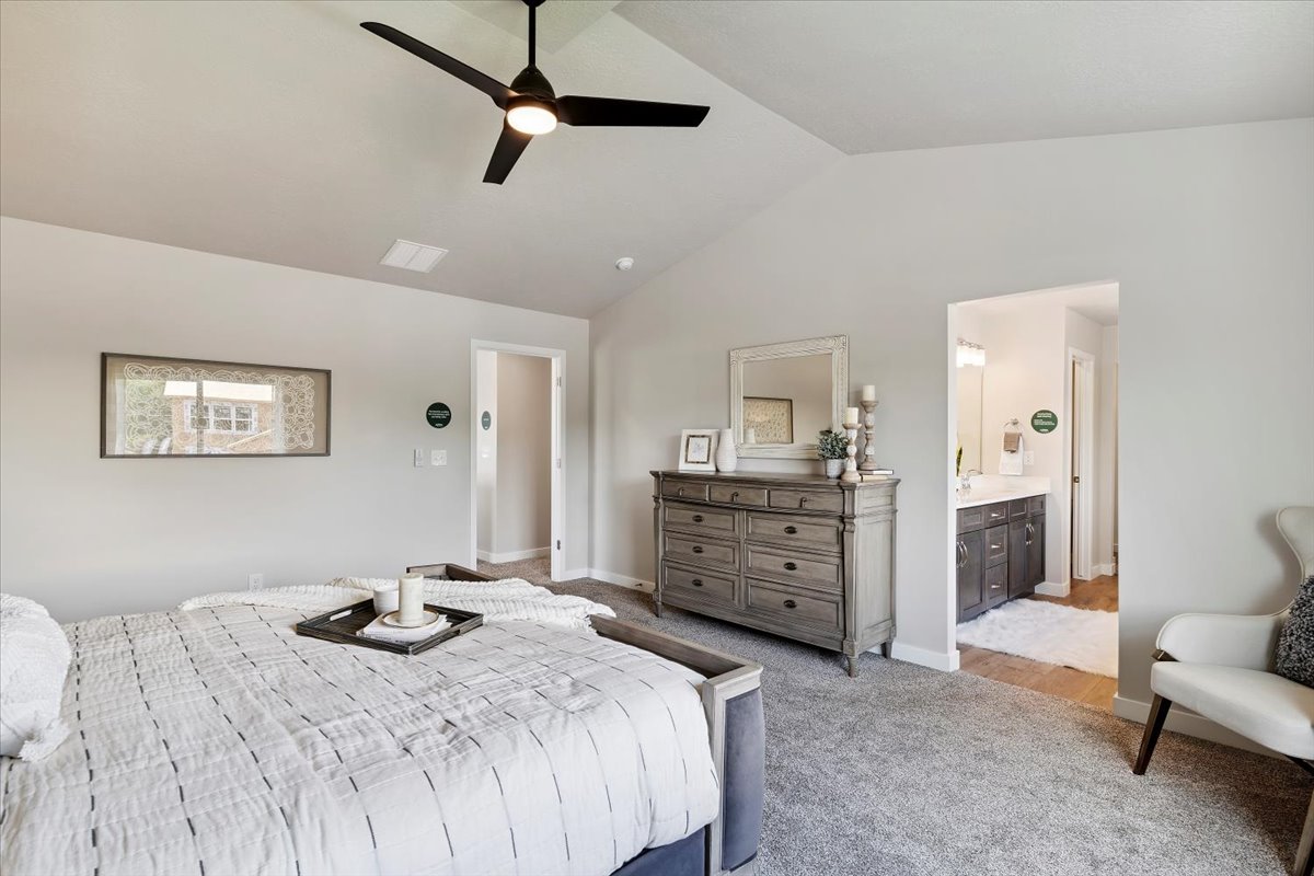 Spacious room featuring vaulted ceilings, a contemporary ceiling fan, and carpet flooring
