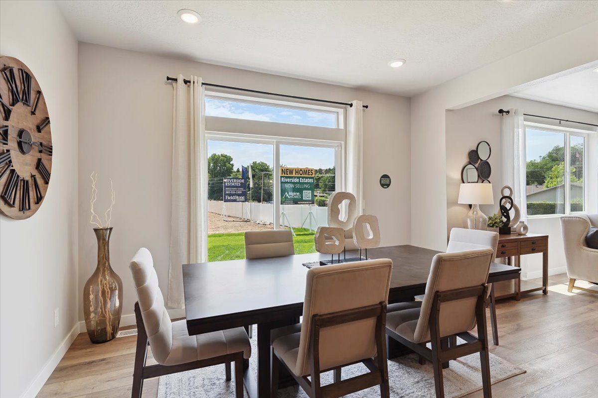 Spacious dining area featuring recessed lighting, large windows with white trim, and wood-finish flooring