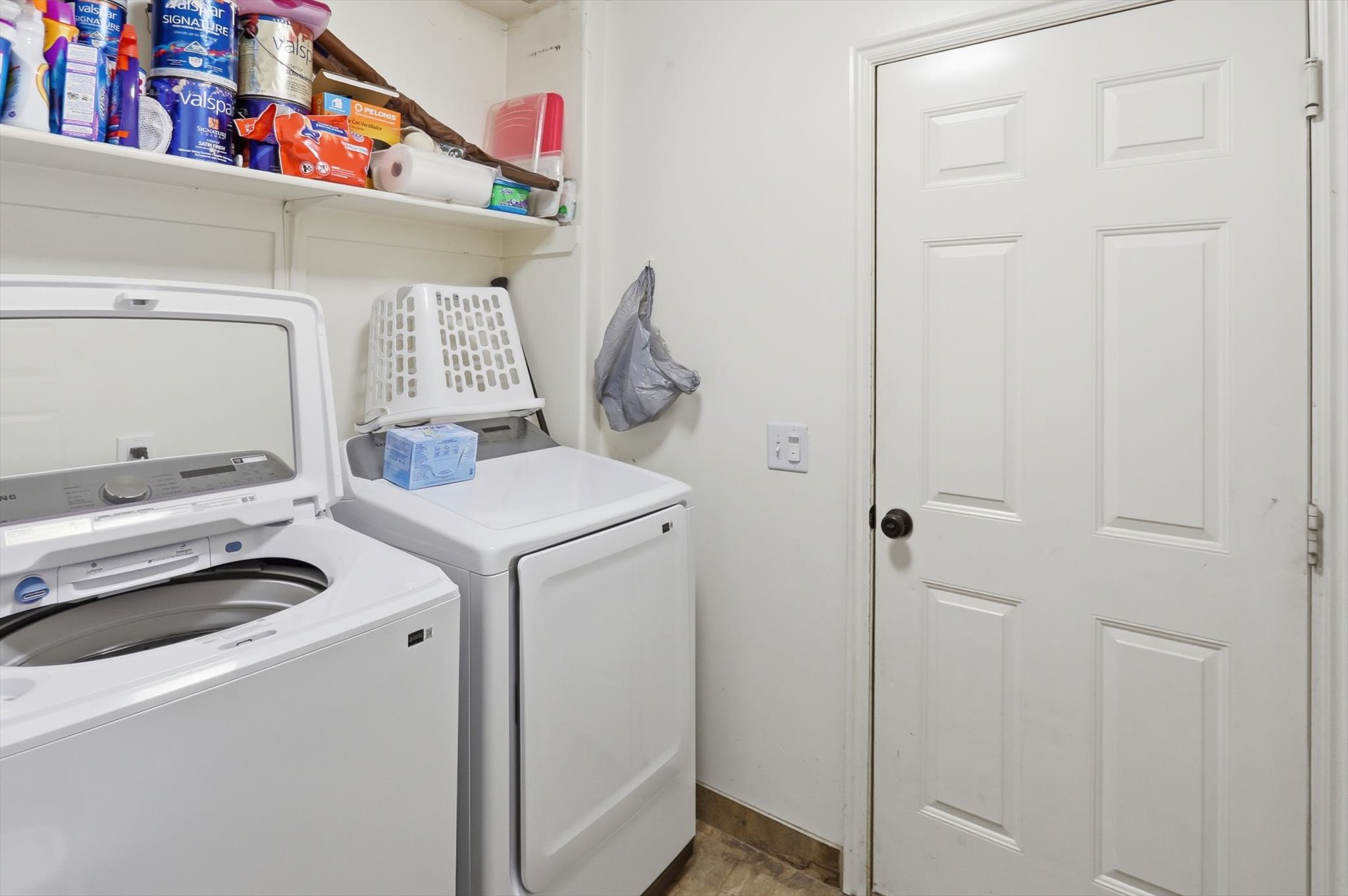 Dedicated laundry area featuring white appliances, a white six-panel interior door, and overhead shelving for storage