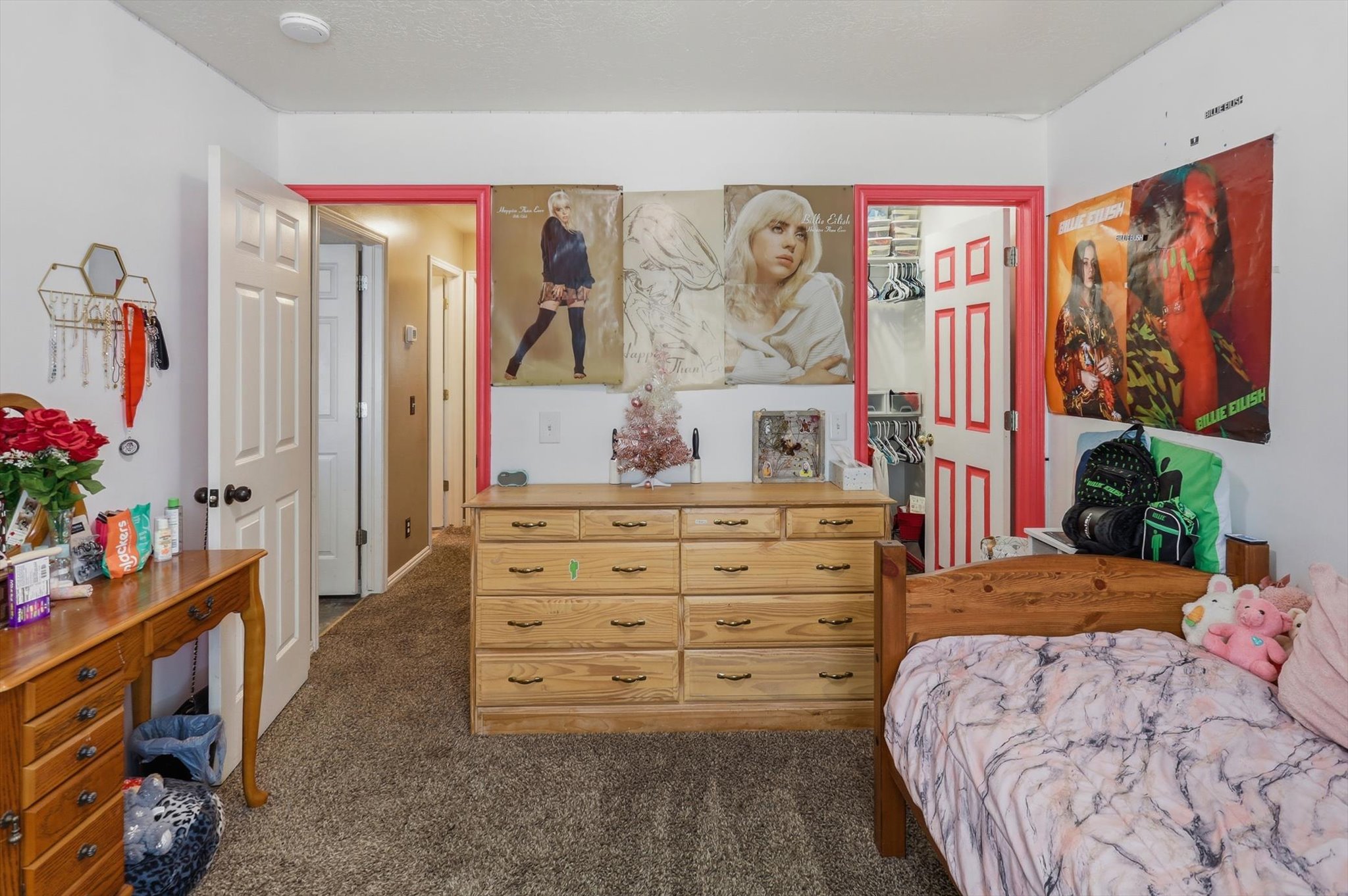 Carpeted room featuring a white paneled door with pink trim, a second white paneled door, and a built-in closet with shelving