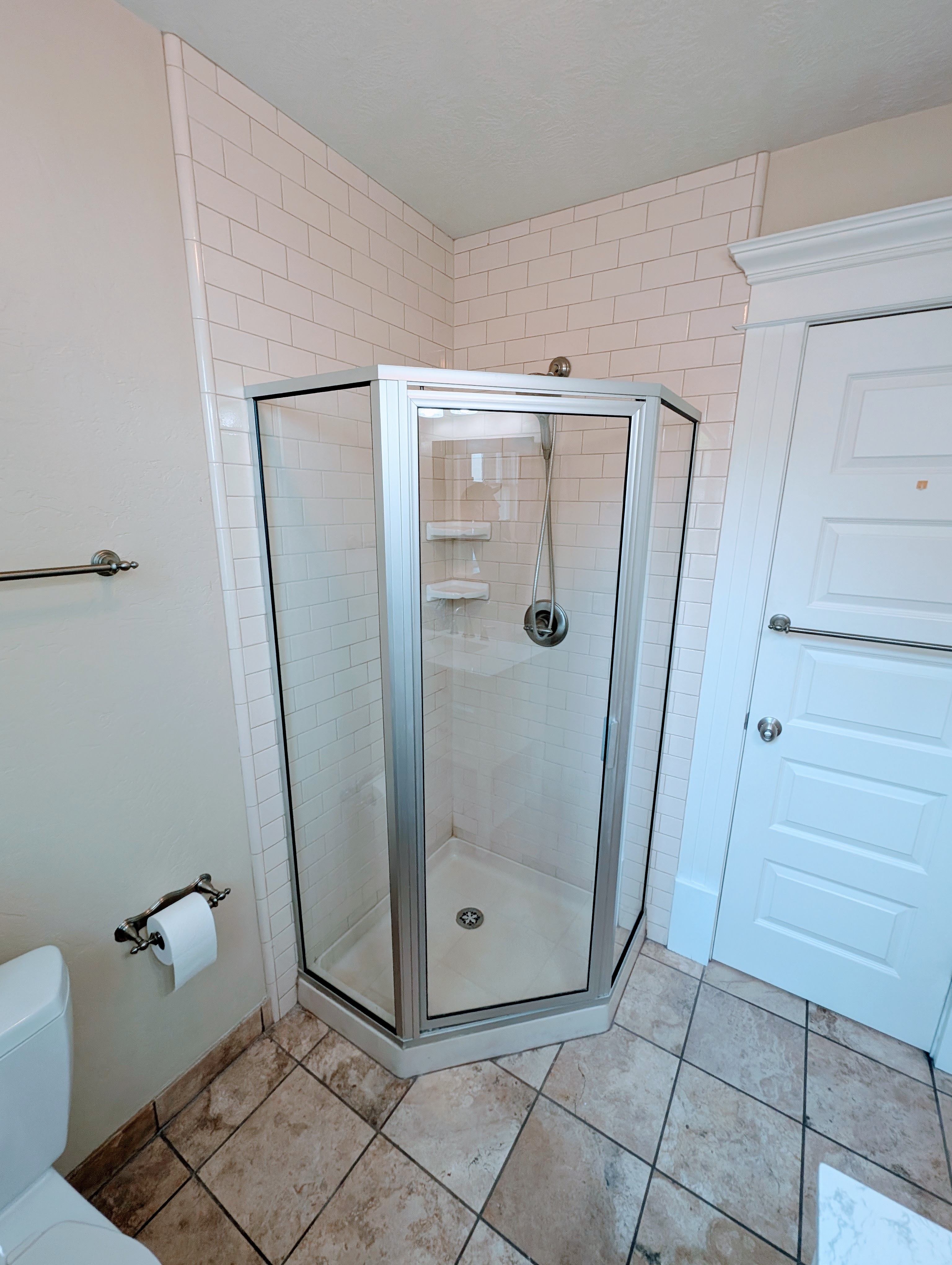 Corner shower enclosure with clear glass panels, subway tile shower surround, and a coordinating shower base