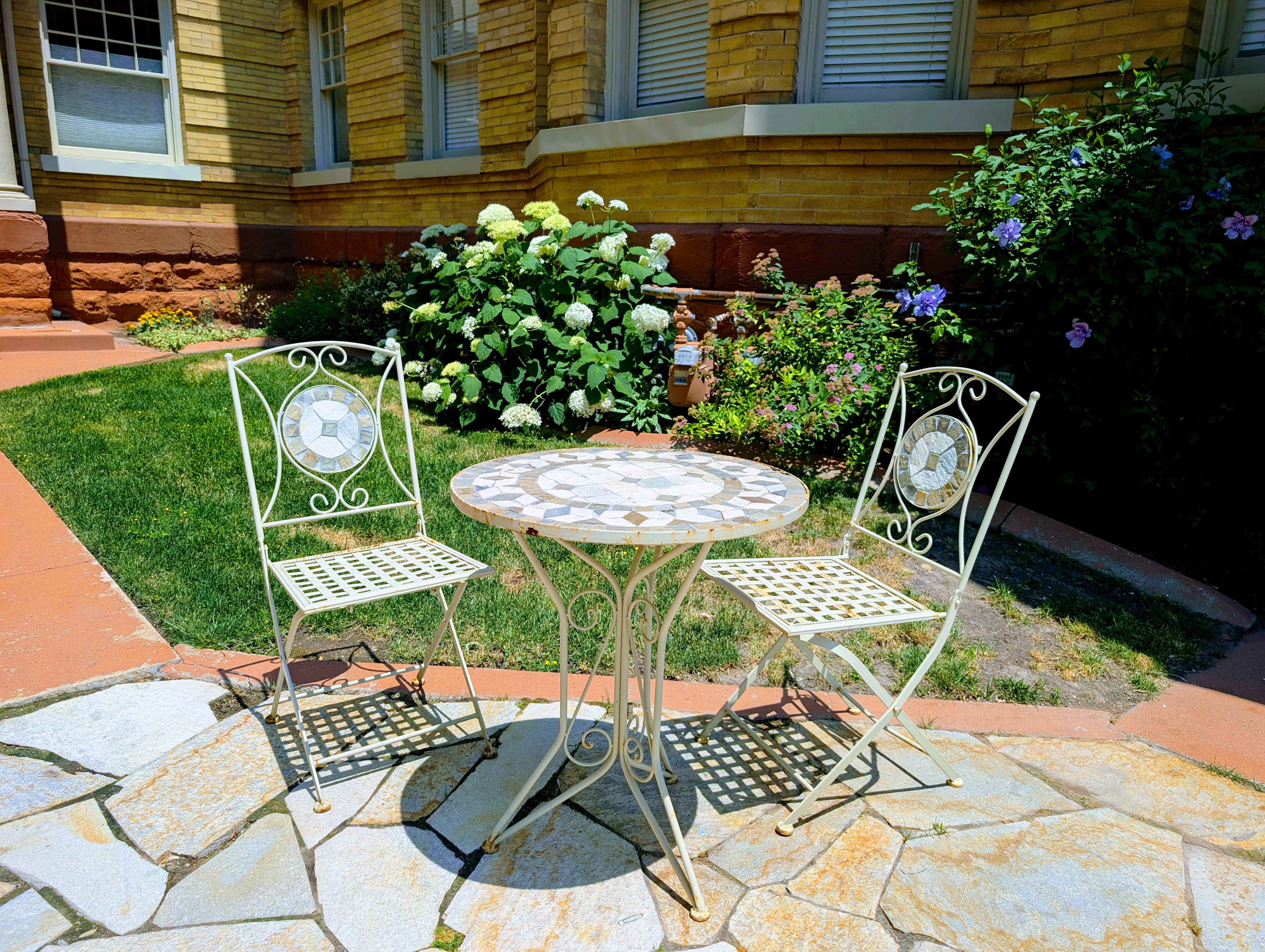 Flagstone patio area with a terracotta border, surrounded by manicured lawn and mature landscaping