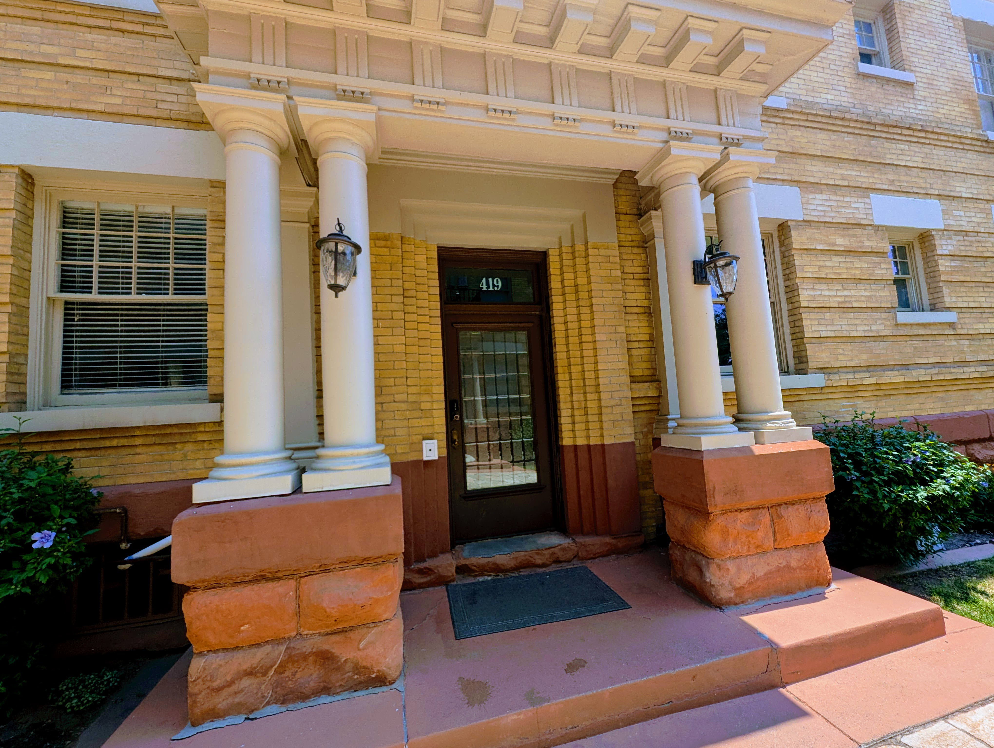 Entryway featuring a rich wood-finish door with glass inserts, flanked by decorative columns