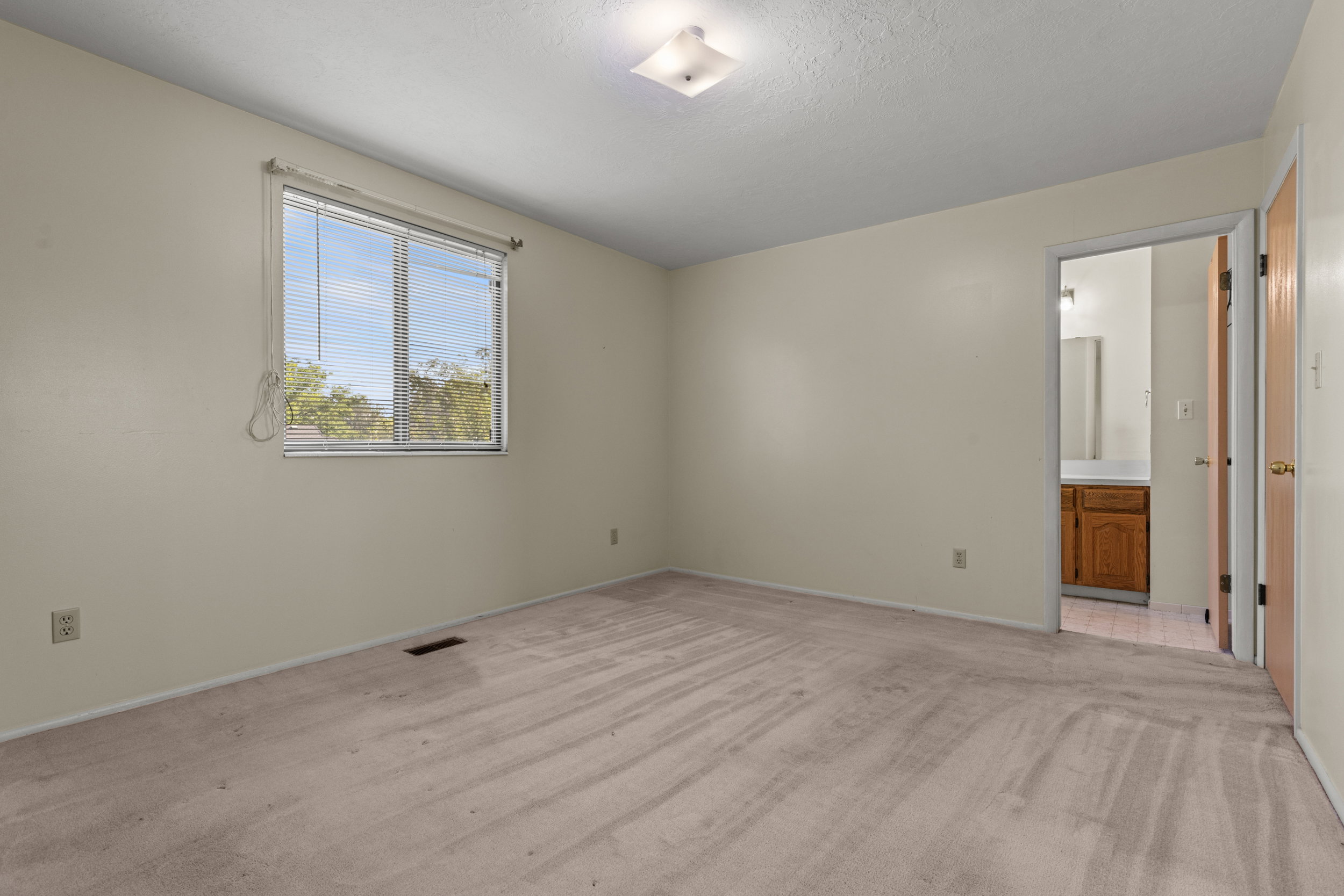 Carpeted room with a single window featuring horizontal blinds