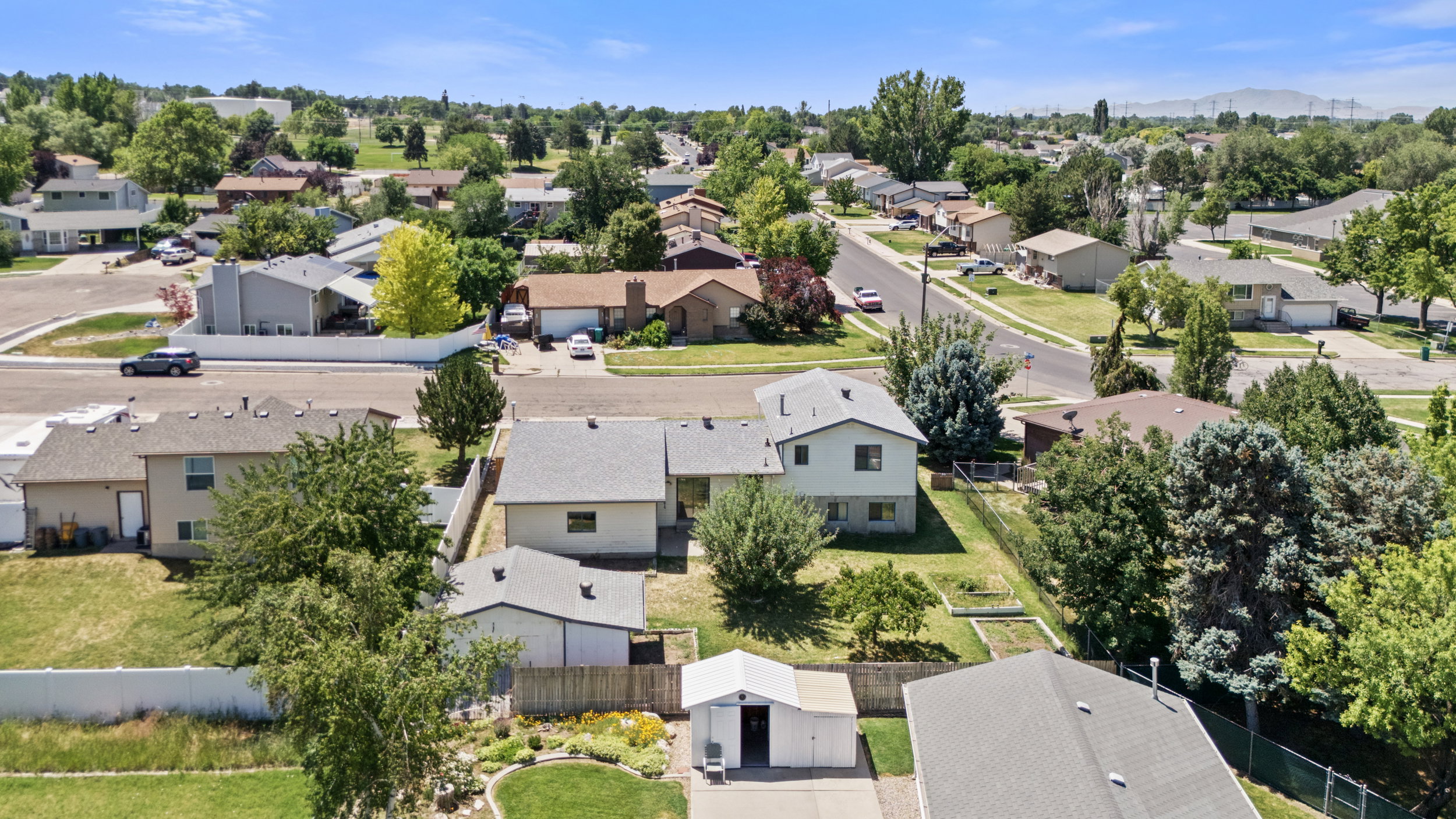 Aerial perspective showcasing the residential neighborhood with mature trees, paved streets, and single-family homes