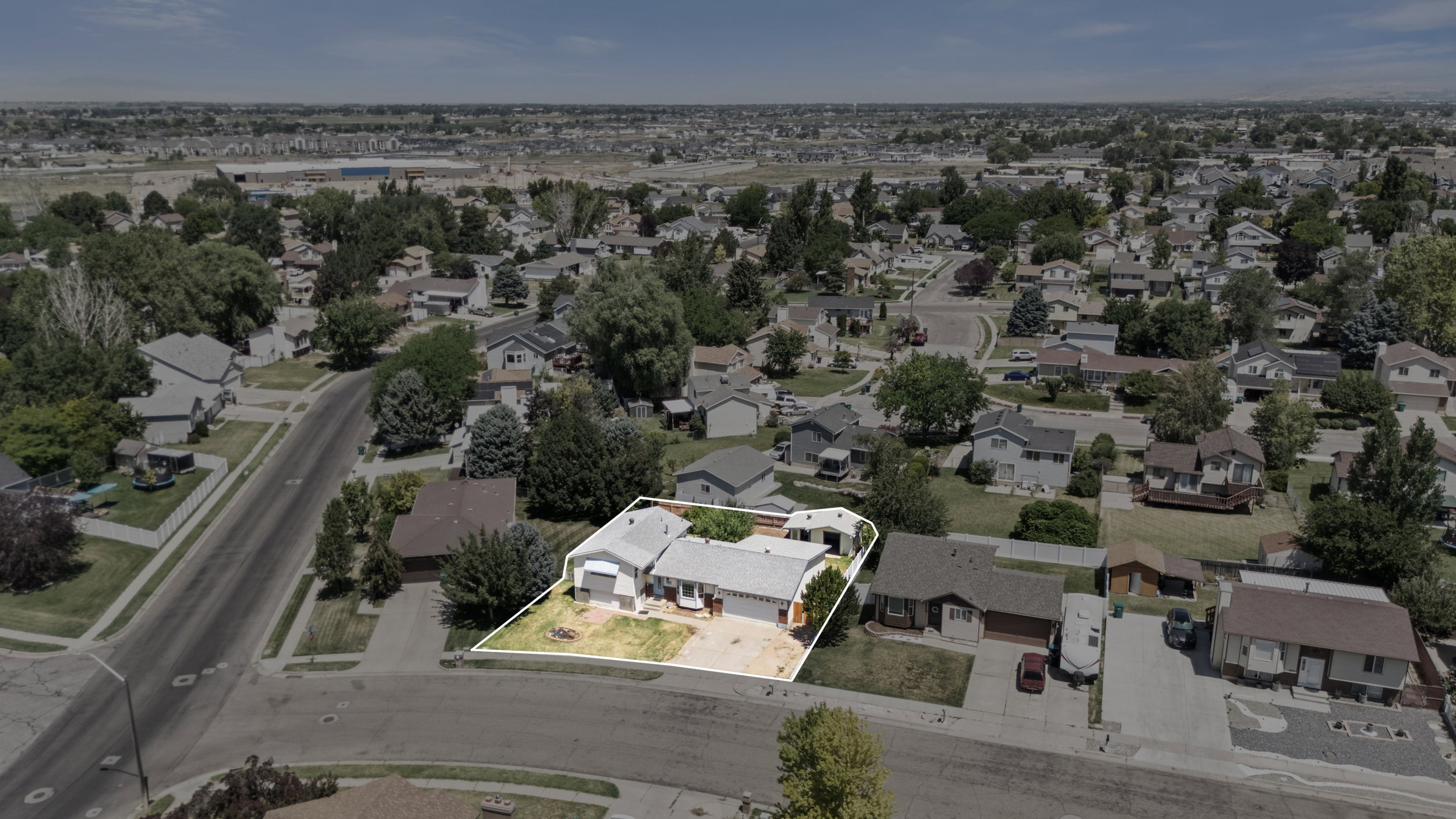 Aerial perspective of a suburban neighborhood, featuring a single-story residence with a white exterior and a light-colored roof