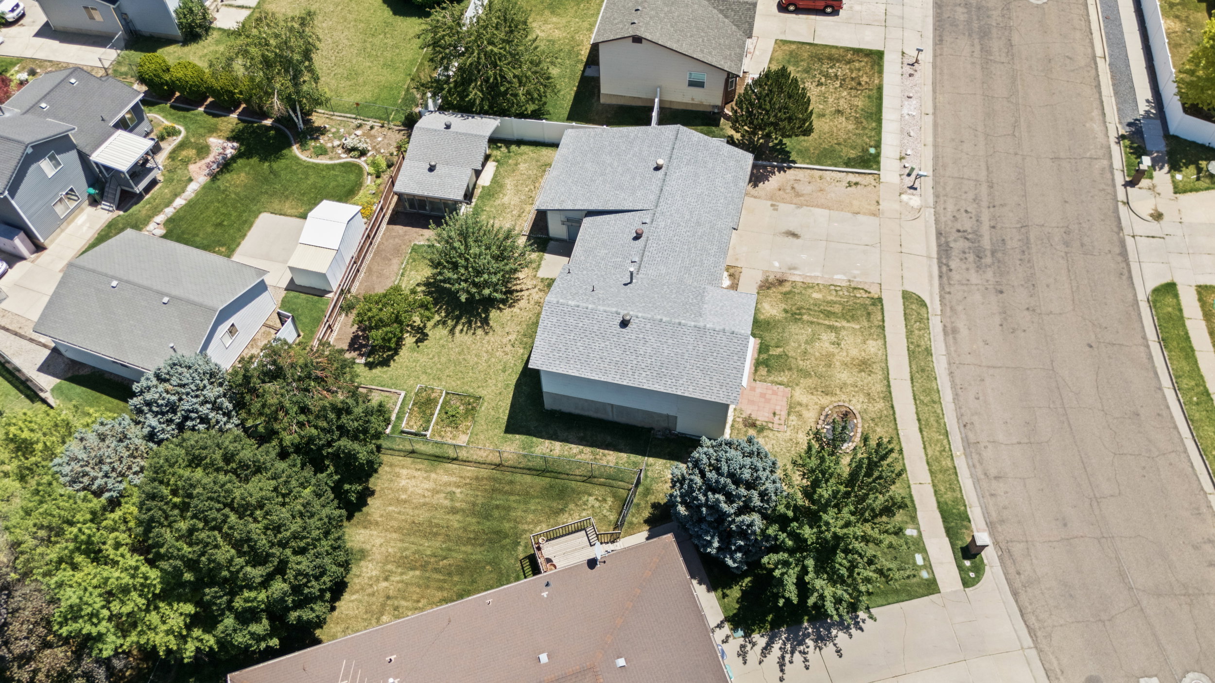 Aerial perspective showcasing a single-story residence with an attached garage, a secondary detached structure, and mature landscaping