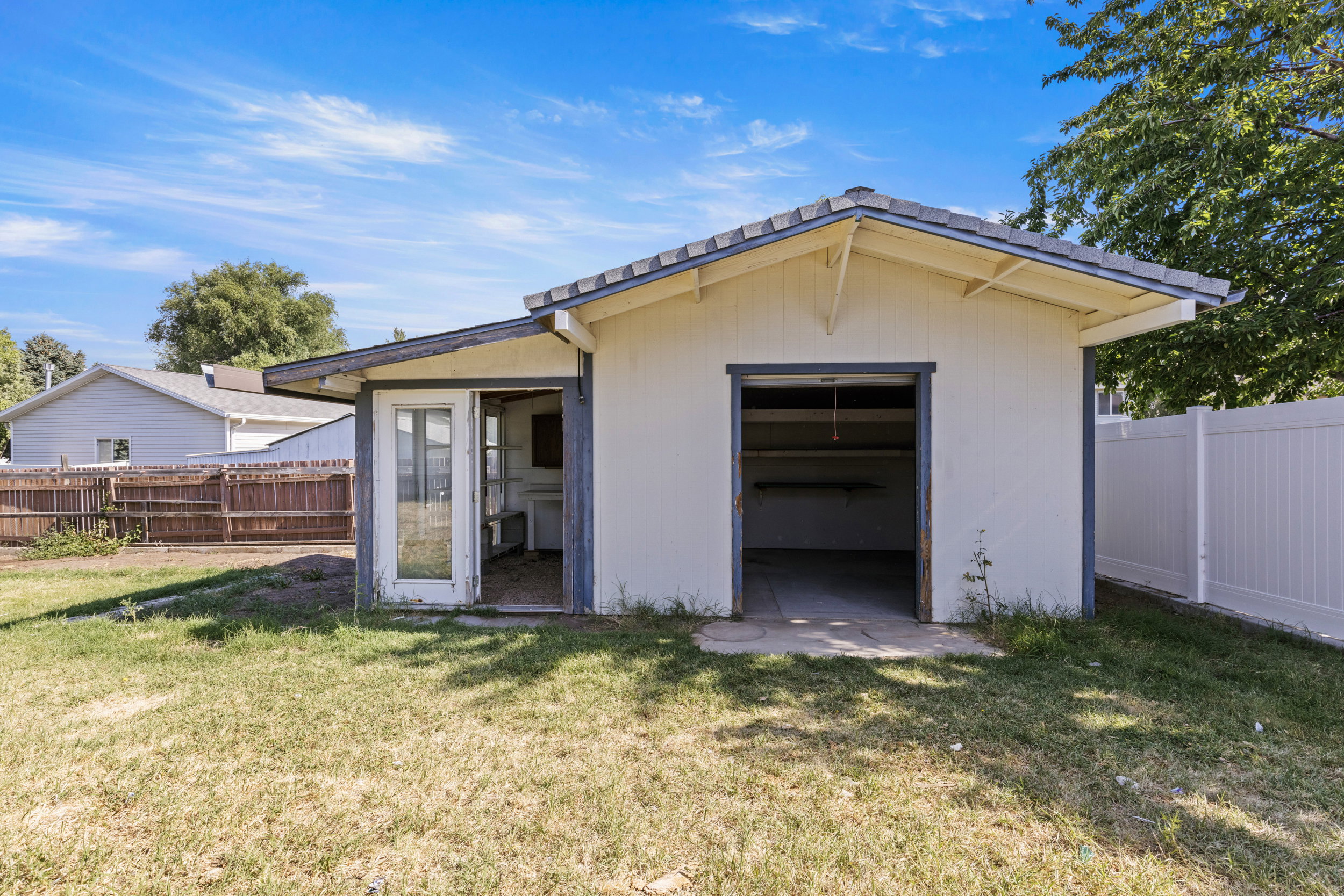Detached outbuilding with a garage bay, side entrance, and open shelving