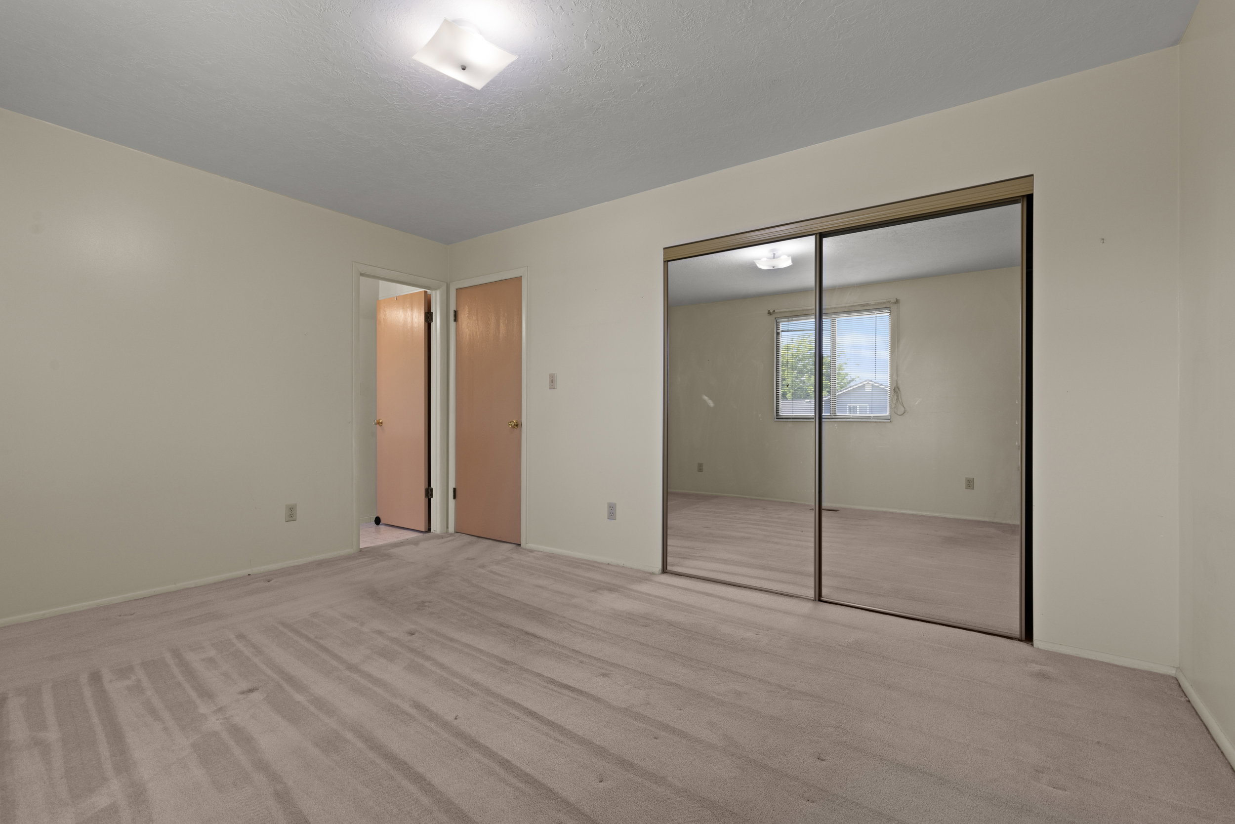 Bedroom featuring neutral-toned walls, plush carpet, and a ceiling-mounted light fixture