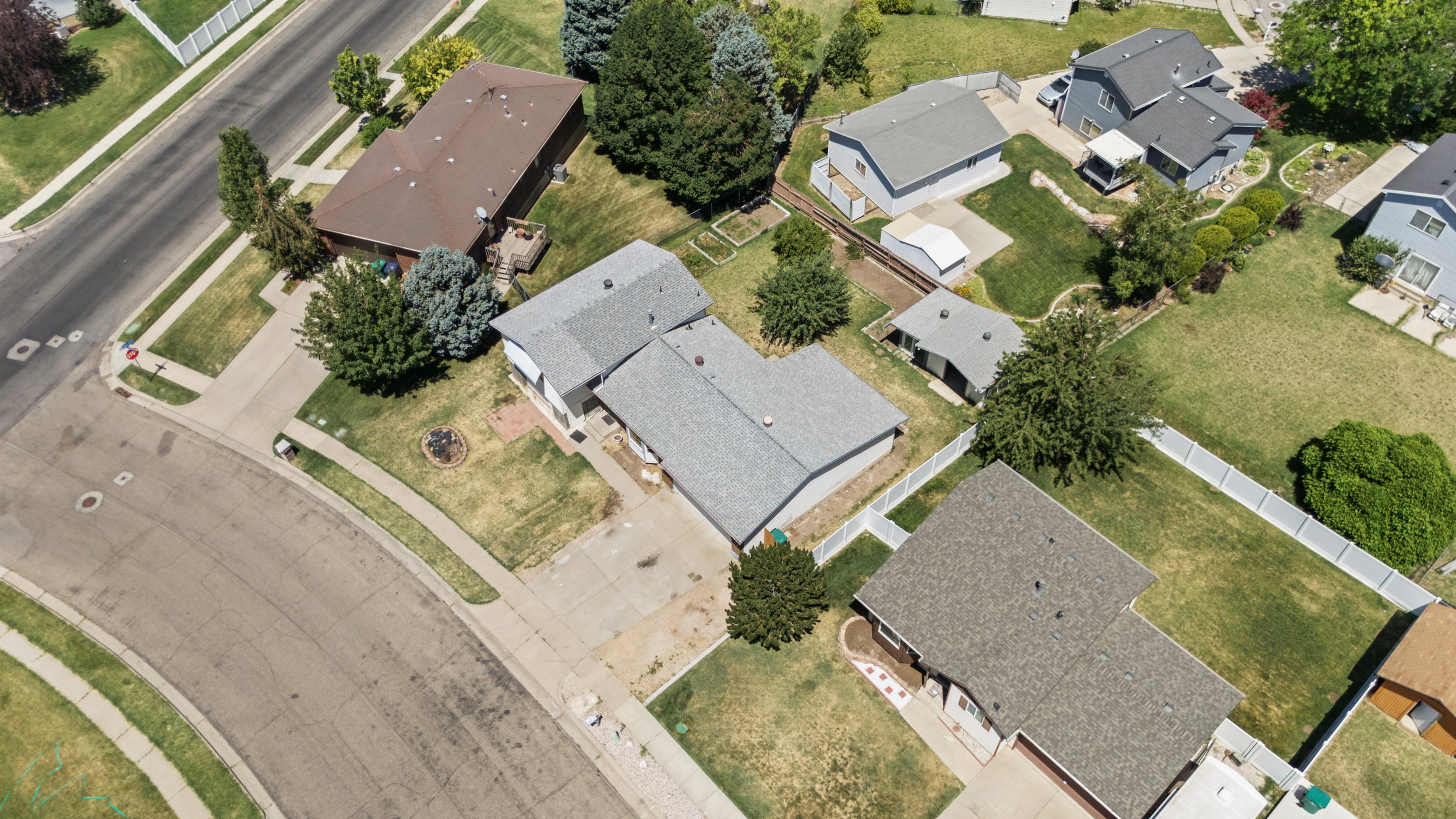 Residential property featuring a shingle roof, paved driveway, and mature landscaping