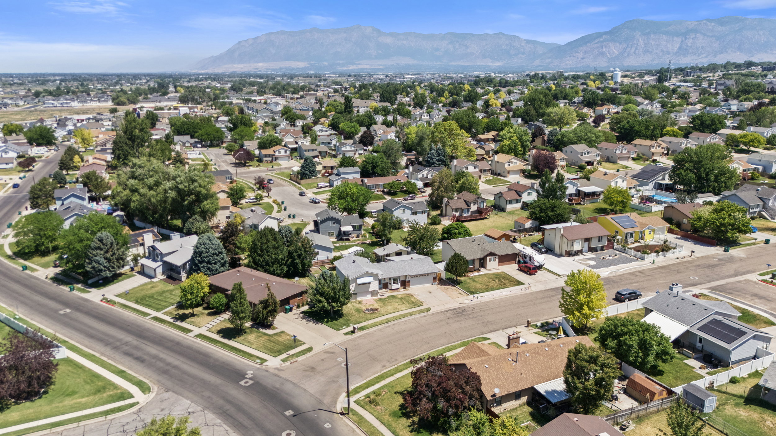 Established residential neighborhood featuring mature trees, paved streets with sidewalks, and a mountain backdrop