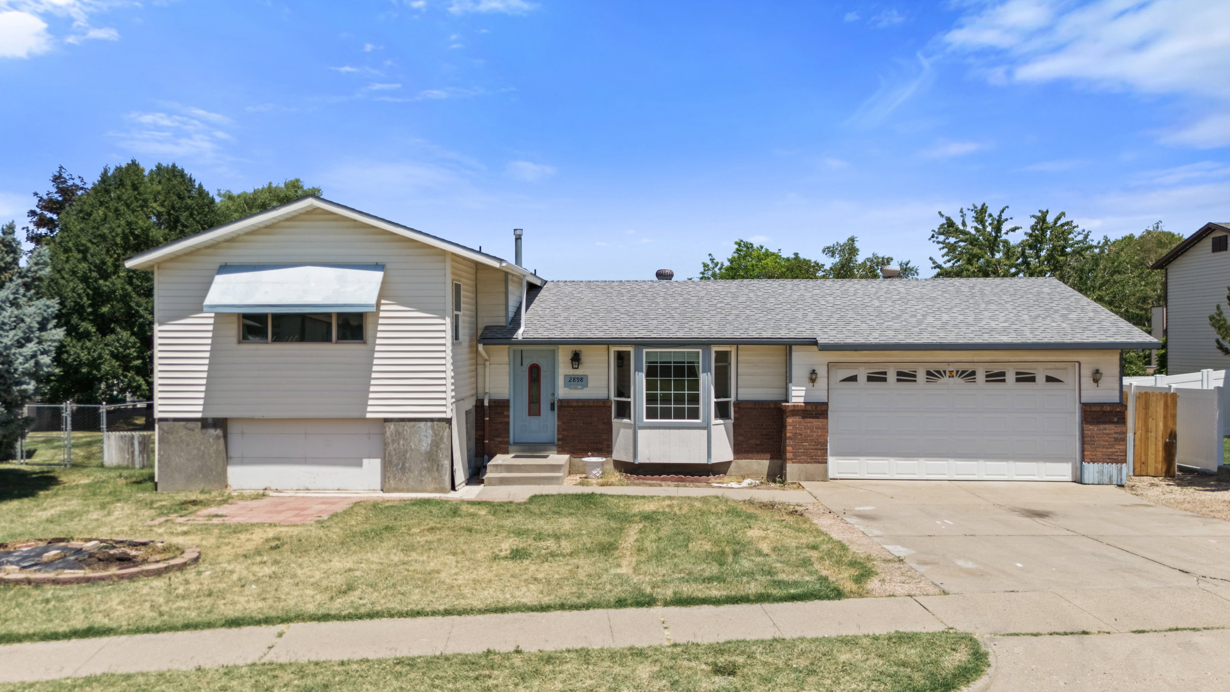 Ranch-style exterior with a two-car garage, partial brick facade, and a bay window feature