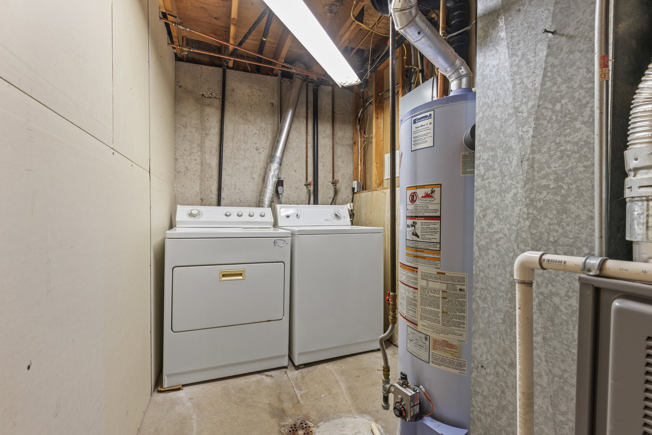 Dedicated laundry area featuring a washer and dryer, water heater, and utility sink