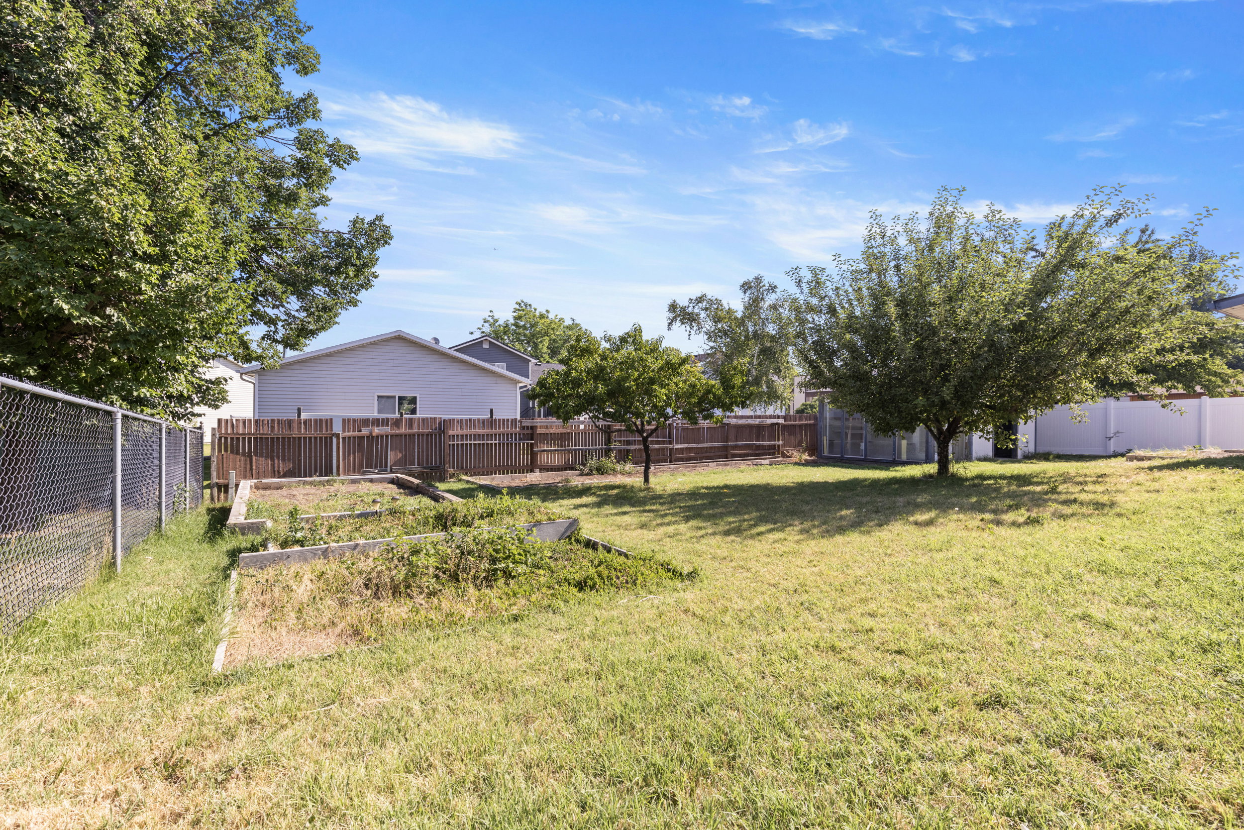 Expansive grassy yard area featuring mature trees and raised garden beds