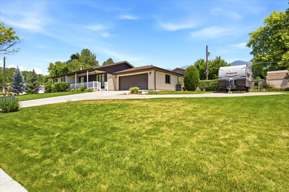 Spacious front lawn with a concrete driveway leading to the attached garage and additional rv parking.