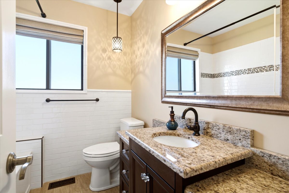 Bathroom vanity with a granite countertop, undermount sink, and dark bronze faucet